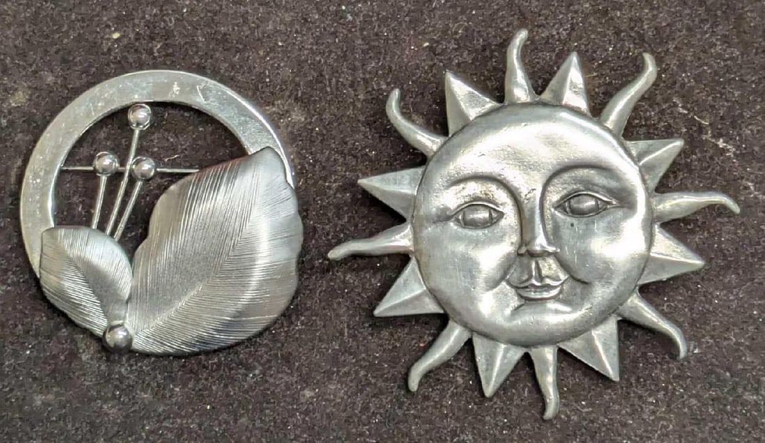 Silver Tone Leaf And Pewter Sun Pewter Brooch Pins: Silver Tone Leaf And Pewter Sun Pewter Brooch Pins. This lot includes: (1) EMJ Silver Tone Modernist Leaf Round Brooch Pin. This is approx 1 1/2" x 1/4" x 1 1/2". Has light scratches. (1)