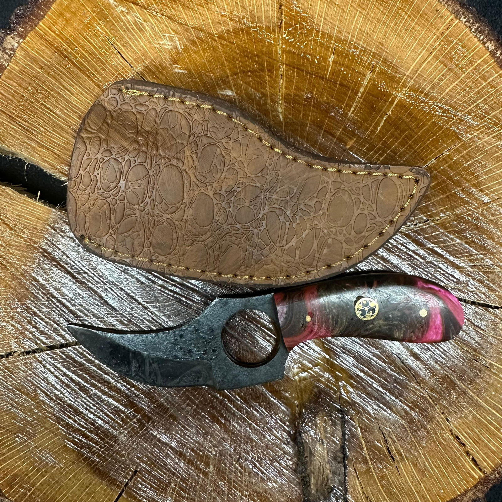 Short Curved Blade Finger Hole Knife MHS Cutlery Pink Design Handle R37: Fixed small finger hole blade knife by MHS Cutlery featuring a black patterned steel blade and decorative spine work. The handle has a contoured, pink epoxy resin/wood-style grip with metal mosaic acc