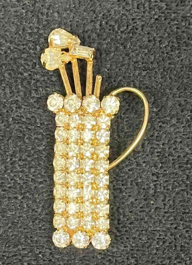 Signed Vintage Gold Tone Hobe Golf Bag Rhinestone Brooch: This lot contains a Signed Vintage Gold Tone Hobe Golf Bag Rhinestone Brooch. It is approx 2" x 1" x 1/2". Total weight is approx 0.3oz. Overall the Hobe Brooch is in good pre owned condition with one