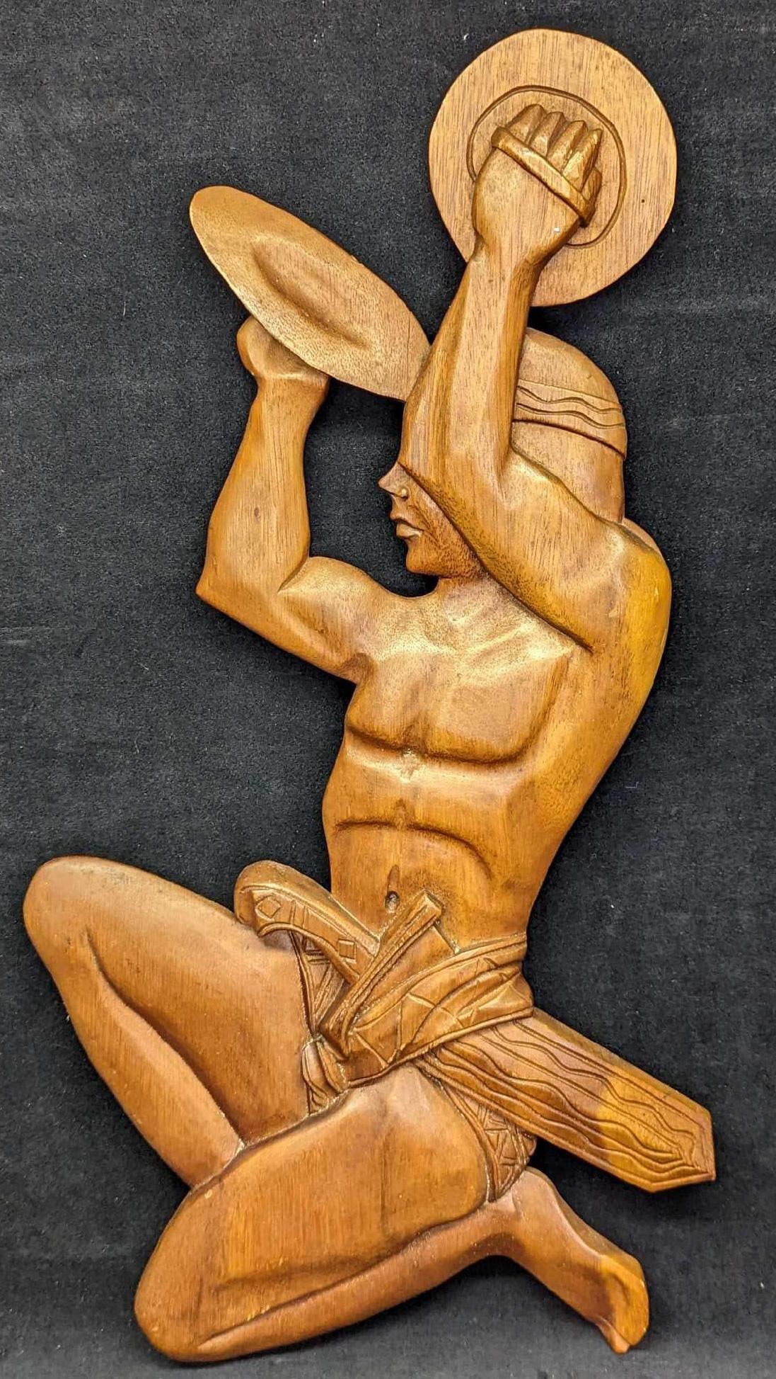 Wooden Wall Art Tribal Man With Cymbals: Wooden Wall Art African Man With Cymbals. Here is wood wall art that shows a tribal banging what appears to be a pair of cymbals together. The maker and date of creation are unknown. The wall art is a