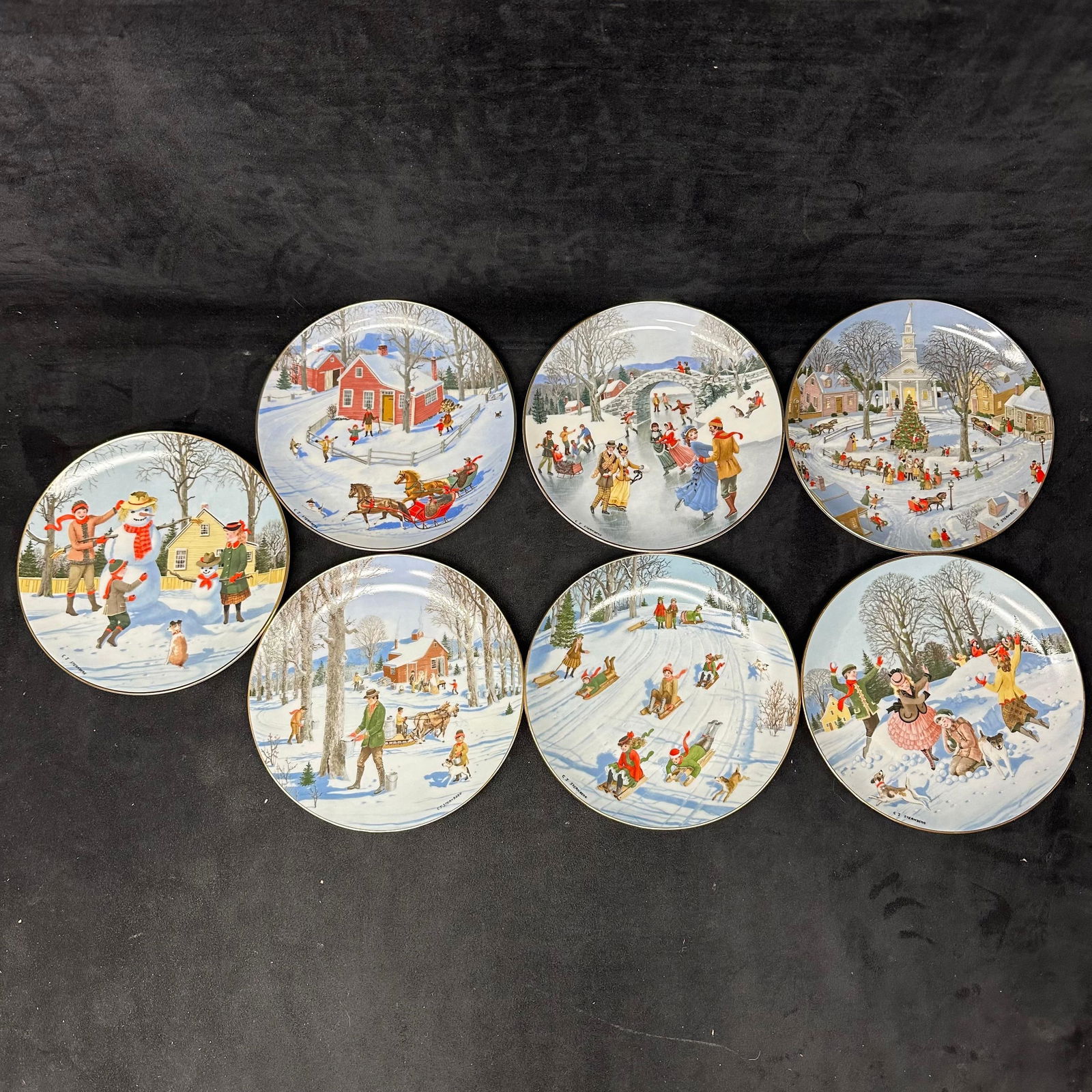 Seven Danbury Mint Old Time Country Winter By Charlotte Sternberg Collector Plates: Group of seven decorative collector plates from the series An Old Time Country Winter by Charlotte Sternberg. Each plate features a different nostalgic winter scene, including titles such as Snowy Fri
