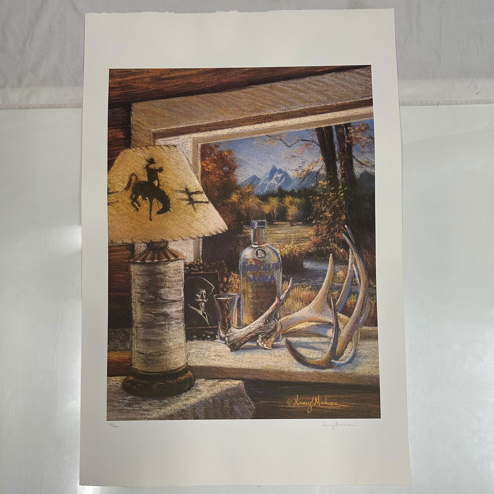 Signed and Numbered Absolut Statehood Wyoming Nancy Madura Print 37/400: Limited edition Absolut Vodka “Statehood” lithograph print on paper. Features the iconic Absolut bottle incorporated into a stylized Wyoming-themed landscape composition. Hand-signed by
