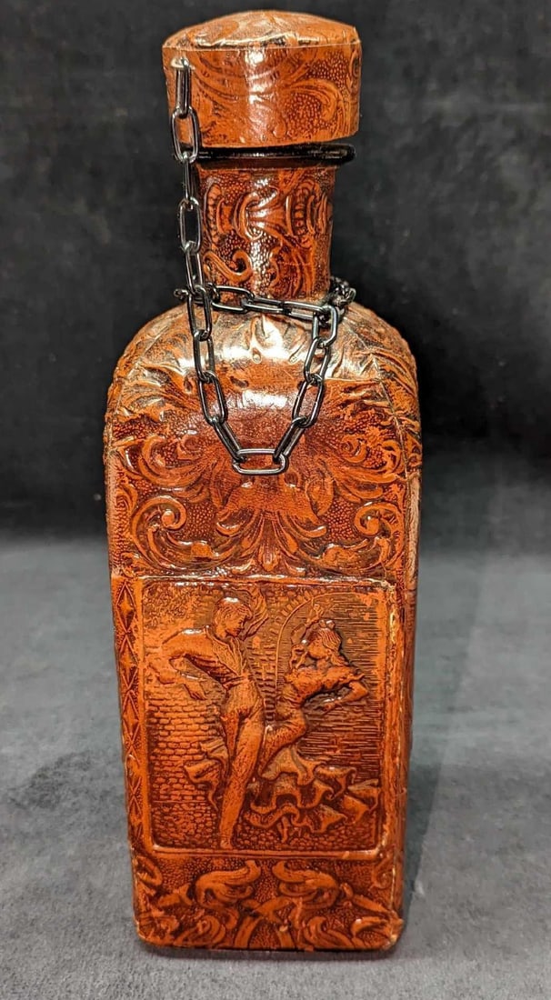 Vintage Tooled Leather Wrapped Decanter: Vintage Tooled Leather Wrapped Decanter. Its maker and date of creation is unknown. This is approx 4" x 4" x 12 1/2" and it weighs 2.82 lbs. There is some wear on the wrap and ripped leather on the