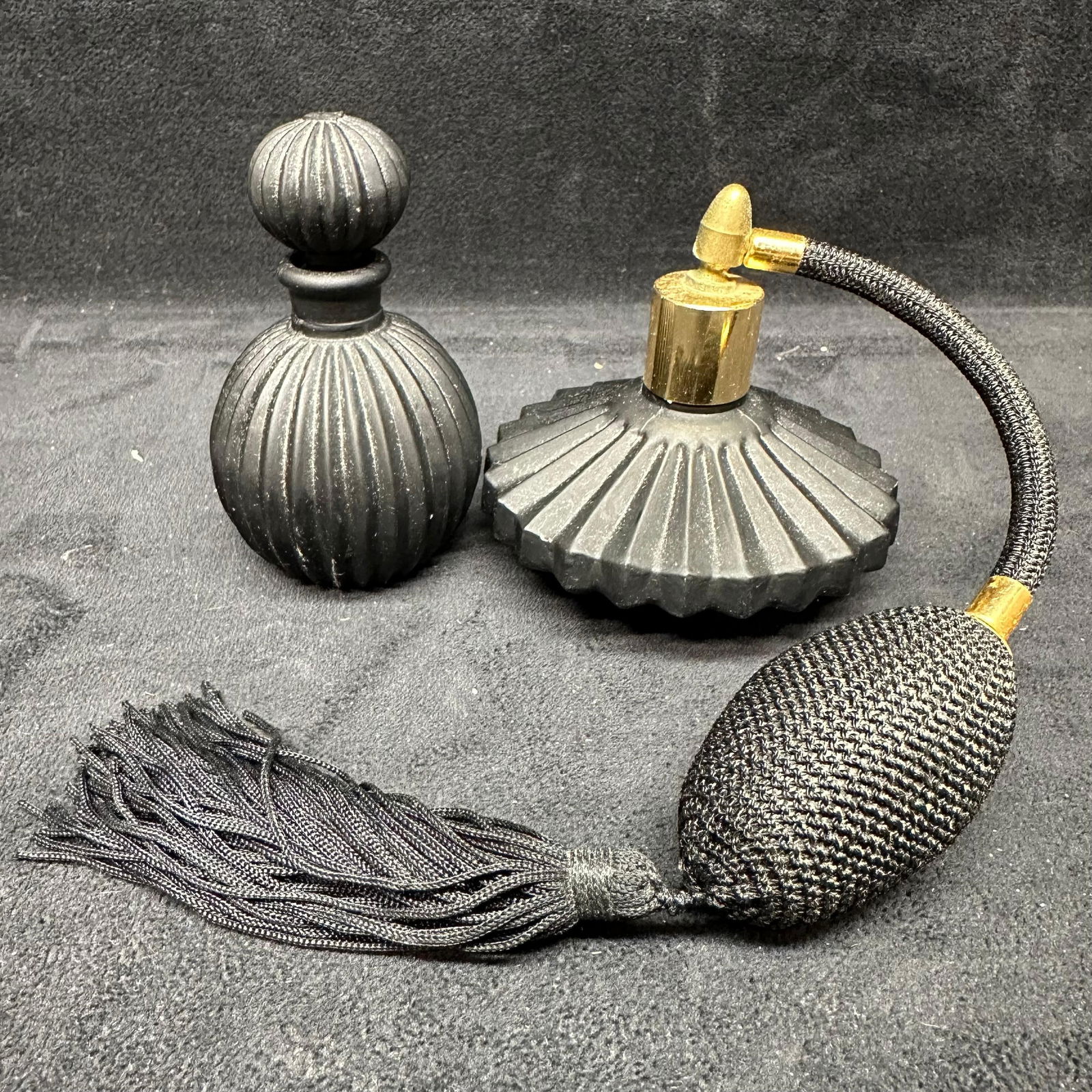 Vintage Black Ribbed Glass Perfume Bottle and Atomizer Set: Two-piece vintage perfume set including a ribbed black glass perfume bottle with stopper and a matching glass atomizer with squeeze bulb. The atomizer features a textured black bulb with gold-tone har