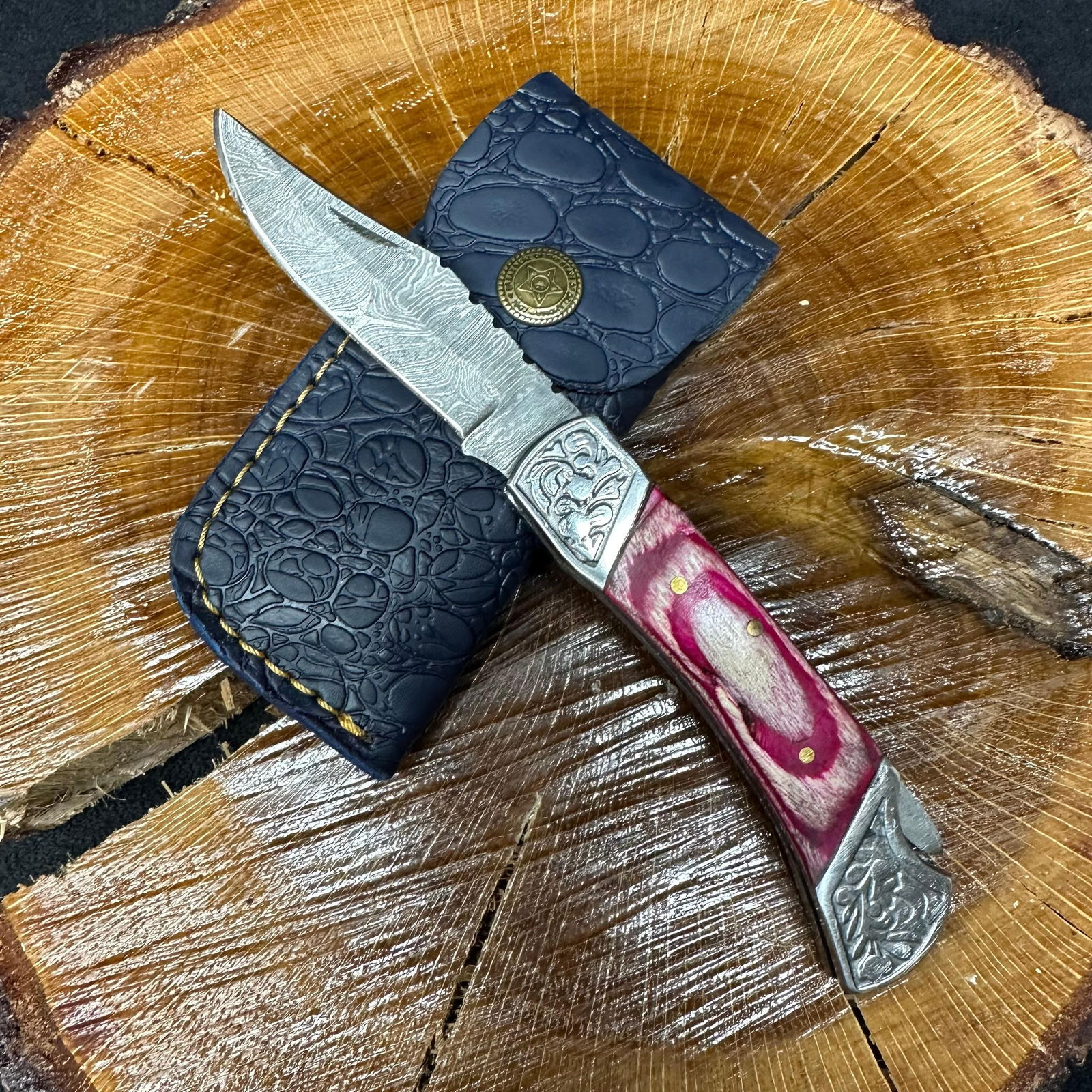 MHS Cutlery Steel Folded Blade Pocket Knife Pink Colorway Handle Q84: Folding blade pocket knife by MHS Cutlery featuring a layered patterned steel blade and decorative spine work. The handle has a contoured, pink wood/resin-style grip with metal mosaic pin accents. Inc