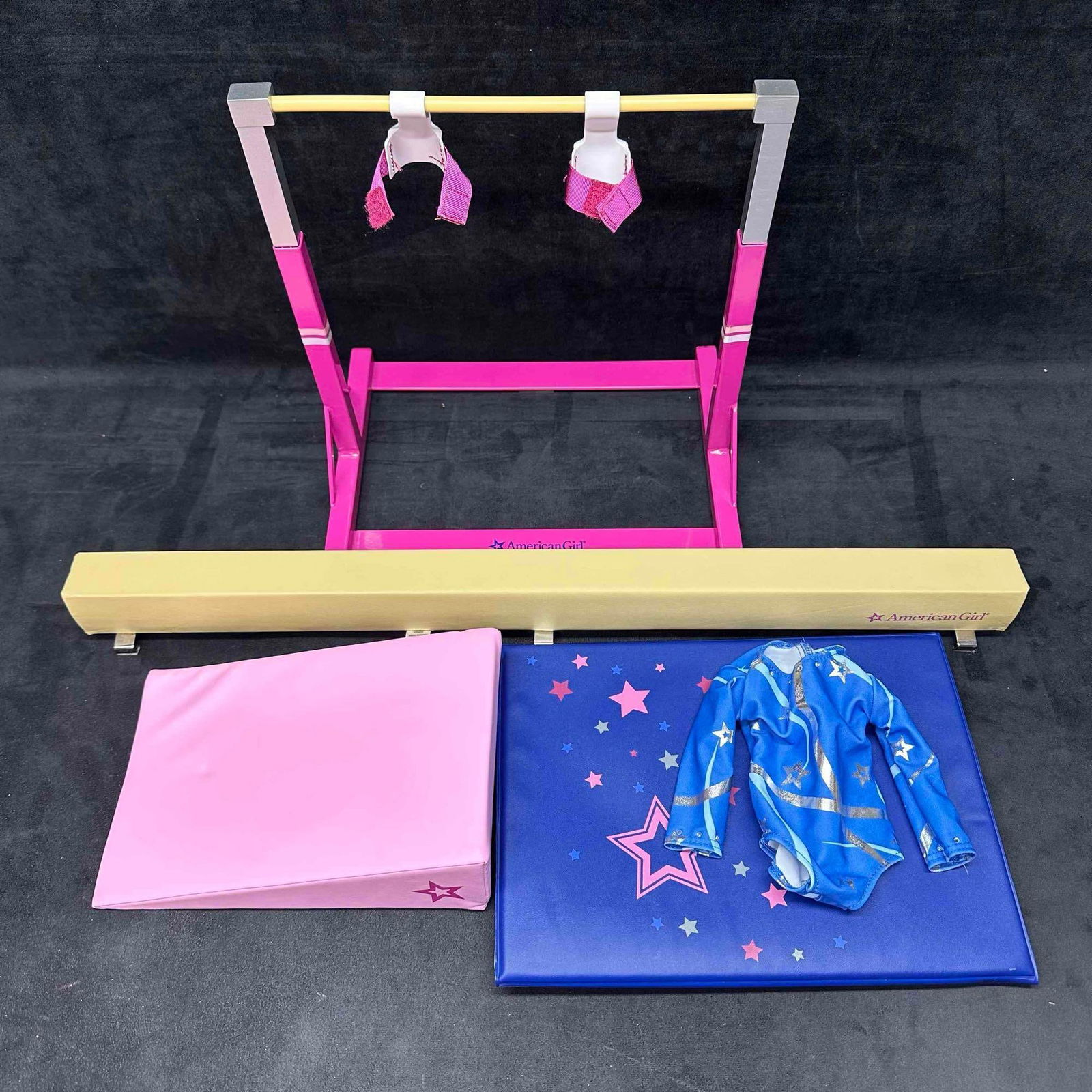 American Girl Gymnastics Set with Bars Balance Beam Mats and Leotard: Original American Girl gymnastics play set including adjustable uneven bars with grips, yellow balance beam, folding star mat, pink wedge mat, and blue star-print leotard. Each piece is branded