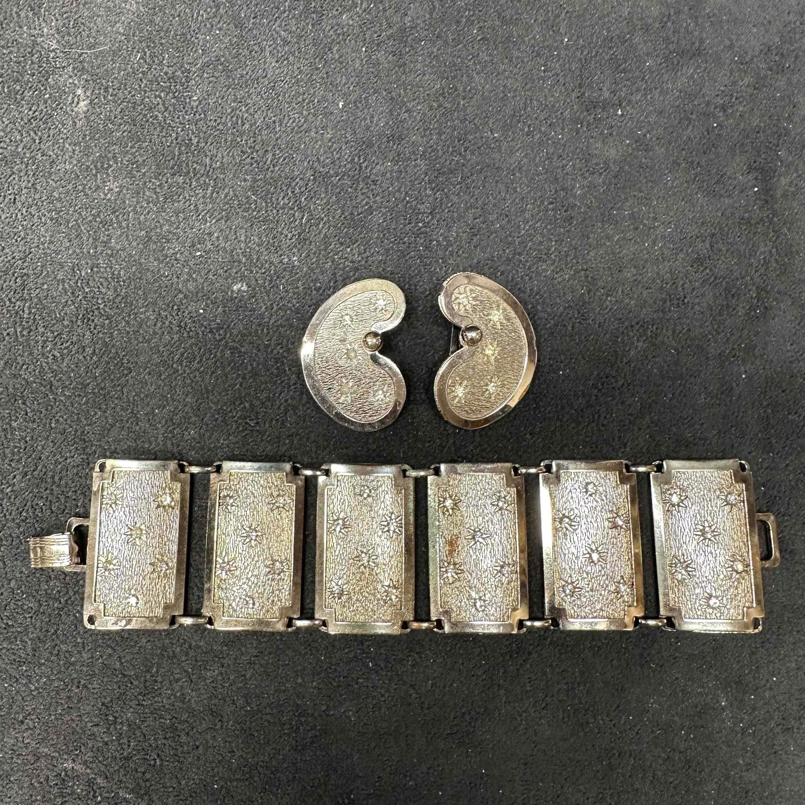 Leru Silver Tone Starburst Bracelet with Matching Earrings Set: Marked Leru, this vintage mid-century set features a wide silver tone link bracelet with textured starburst panels and a pair of matching kidney-shaped clip-on earrings. Bracelet consists of six recta