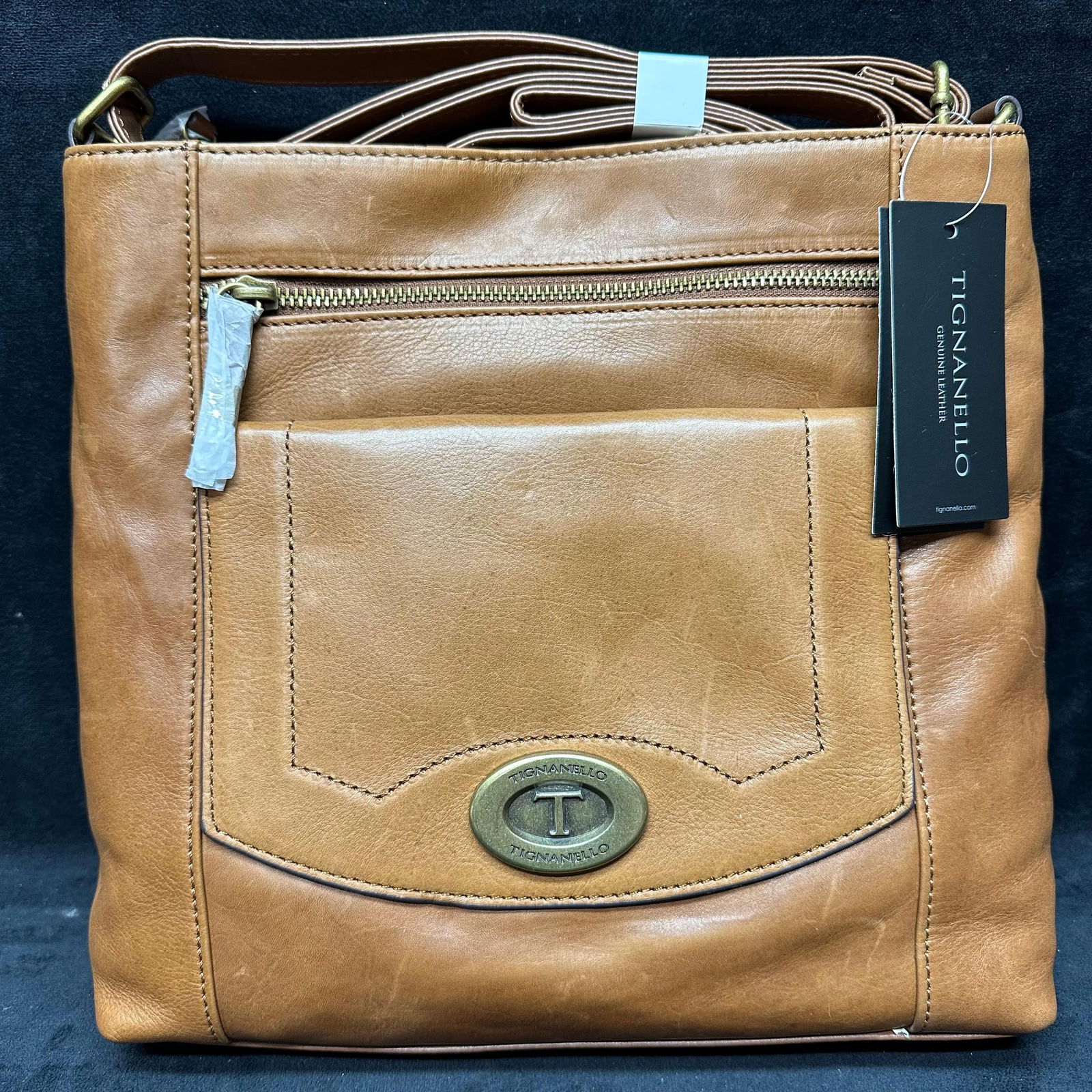 Tignanello Genuine Leather Crossbody Shoulder Bag Brown Walnut Cognac: Tignanello brand crossbody/shoulder bag crafted from genuine leather in a brown walnut/cognac finish. Features an adjustable leather strap, exterior zip pocket, front slip pocket with logo medallion,