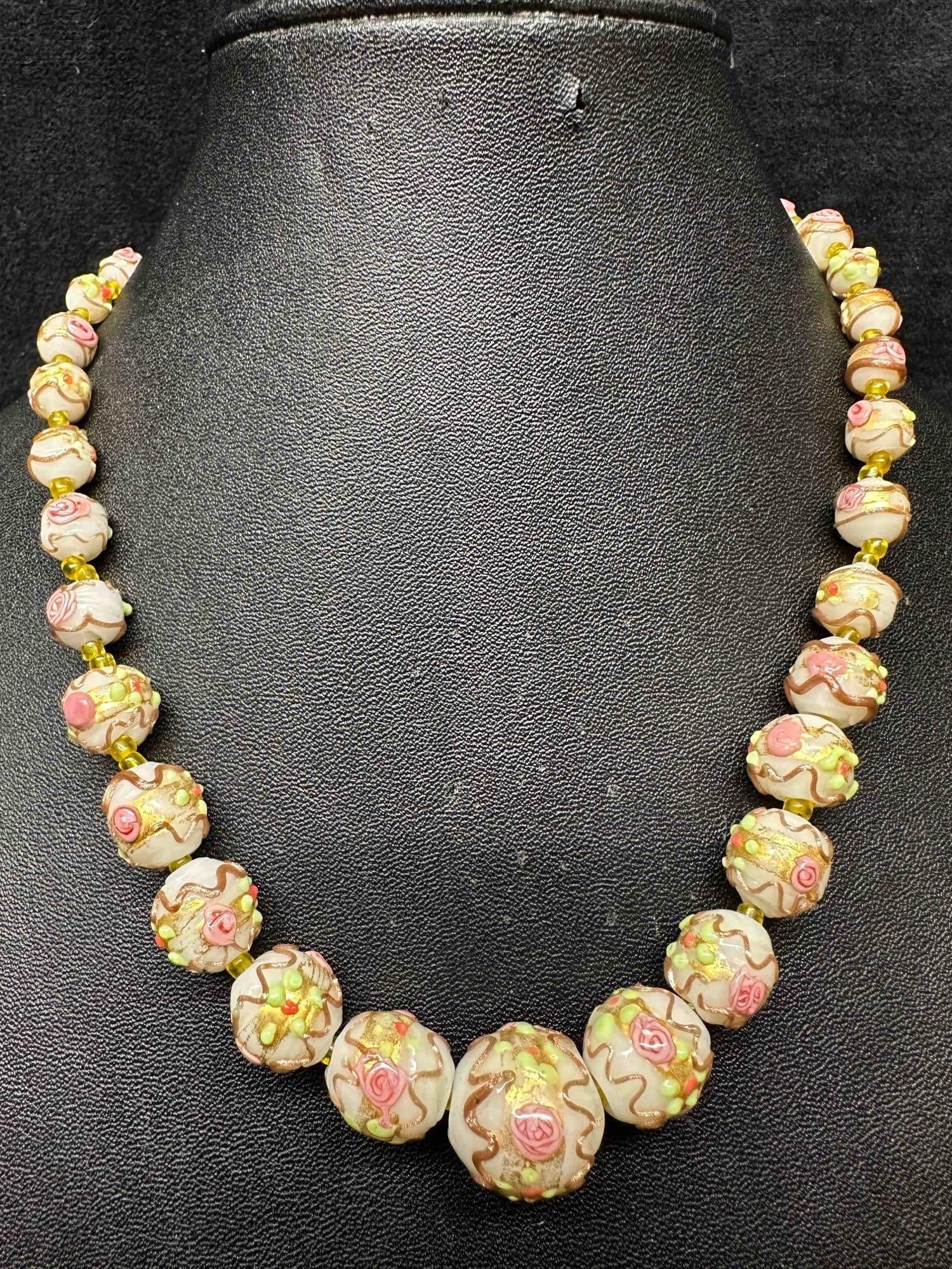 Murano Venetian Lamp Work Art Glass White Floral Pink Green Copper Accents Beaded Necklace F10: Murano Venetian Lamp Work Art Glass White Floral Pink Green Copper Accents Beaded Necklace F10. Necklace with white colored glass beads with a beautiful design on each. The necklace features floral an