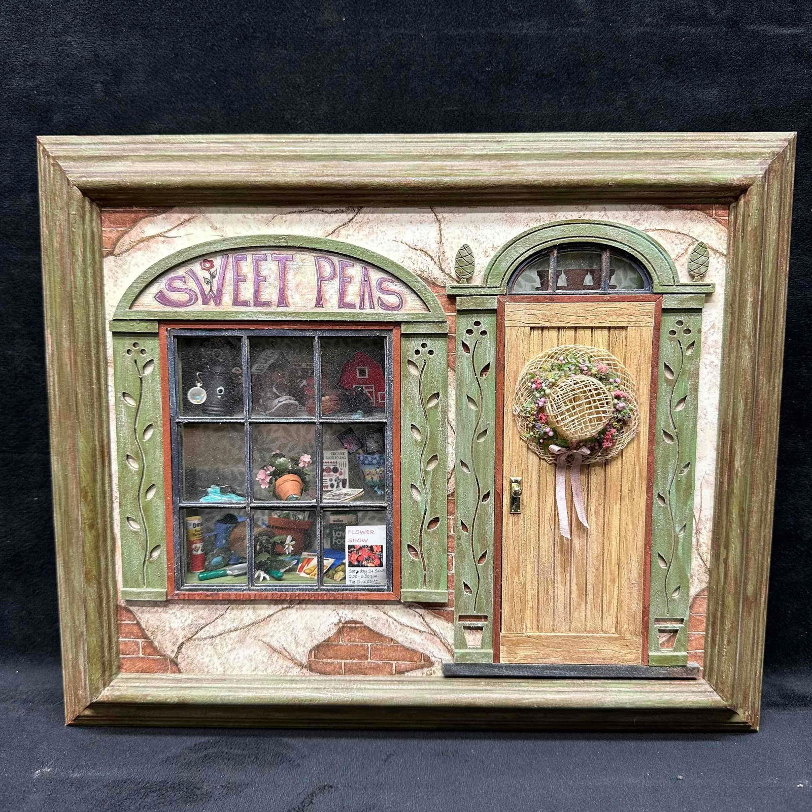 Robin Betterley Sweet Peas Miniature Shadowbox Shop Wall Hang Art: Miniature wall-hanging shadowbox by Robin Betterley’s Miniatures, titled Sweet Peas. Features a shop front with door and wreath, along with a detailed window display containing gardening tools, seed