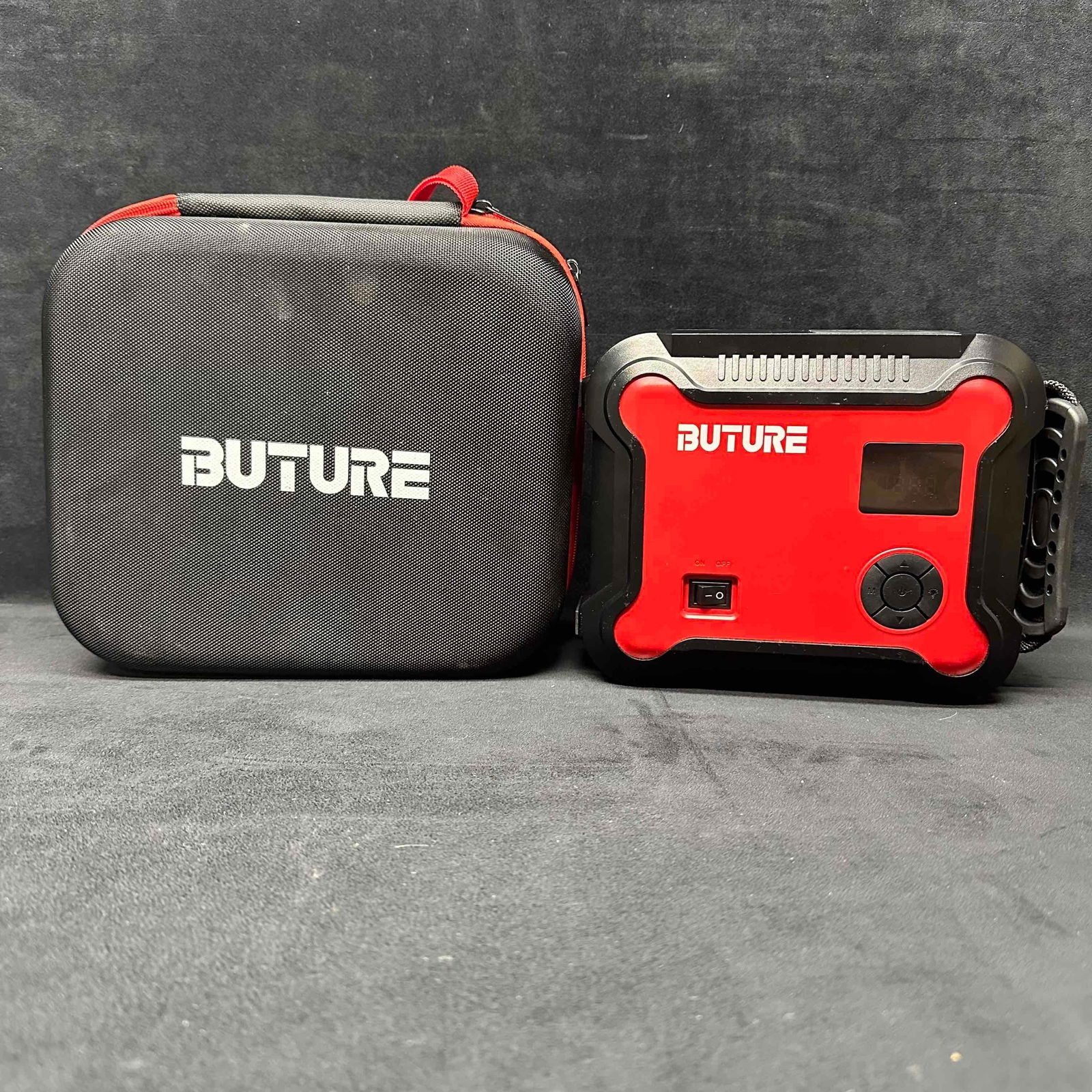 Buture Portable Car Jump Starter and Air Compressor with Carry Case BR700: Buture BR700 portable jump starter and air compressor combo. Compact design with a red and black hard shell carrying case. Digital display with PSI reading, multiple mode options, and built-in light.