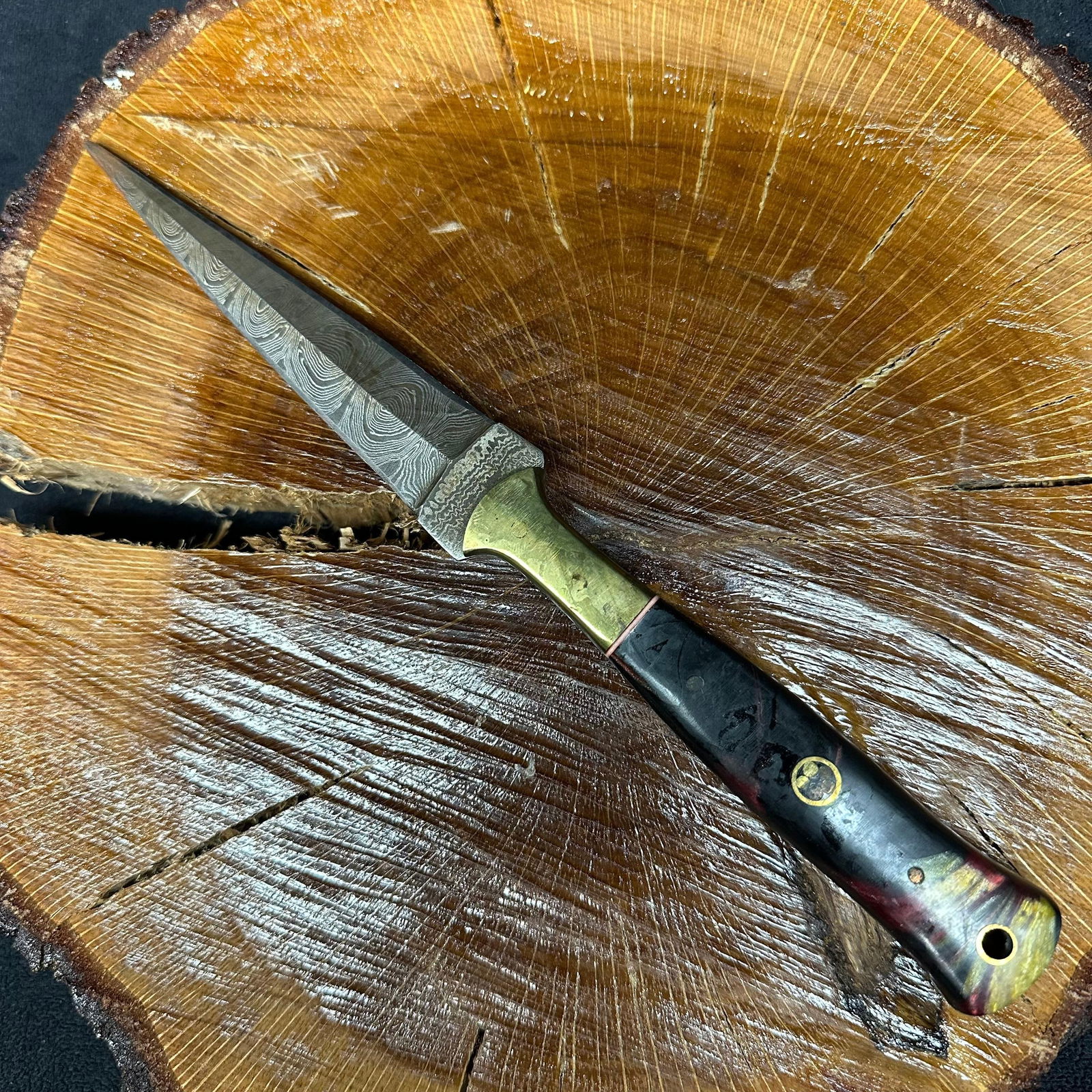 MHS Cutlery Steel Fixed Blade Dagger Knife P64: Fixed dagger-style blade knife by MHS Cutlery featuring a textured steel blade and decorative spine work. The handle has a contoured, red and black-colored resin-style grip with metal mosaic pin accen