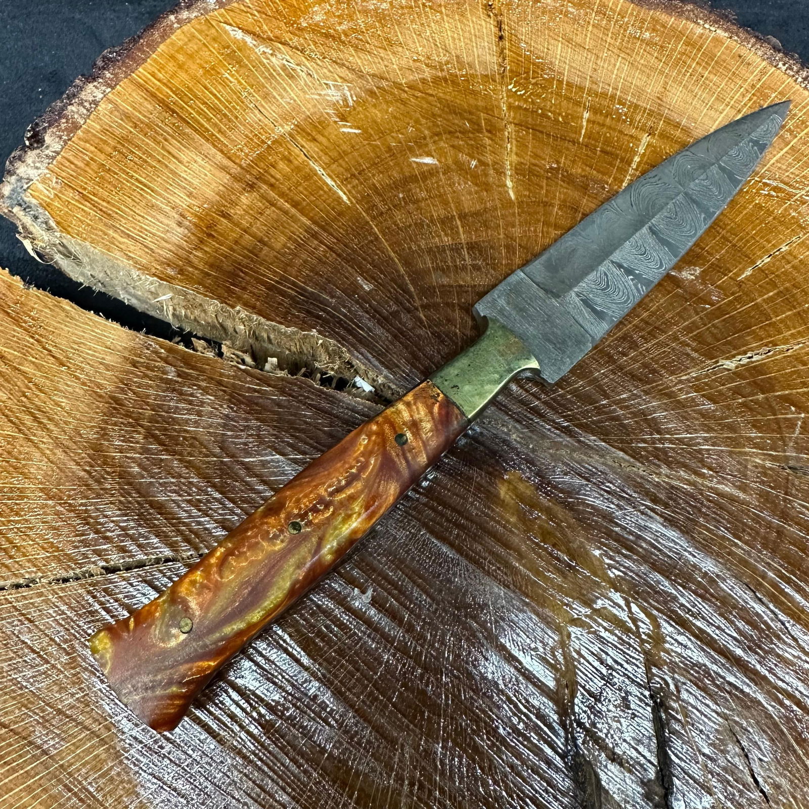 MHS Cutlery Steel Dagger Blade Knife Metallic Orange Red Yellow Hues: Fixed dagger-style blade knife by MHS Cutlery featuring a textured steel blade and decorative spine work. The handle has a contoured, red-colored resin-style grip with metal mosaic pin accents. Includ