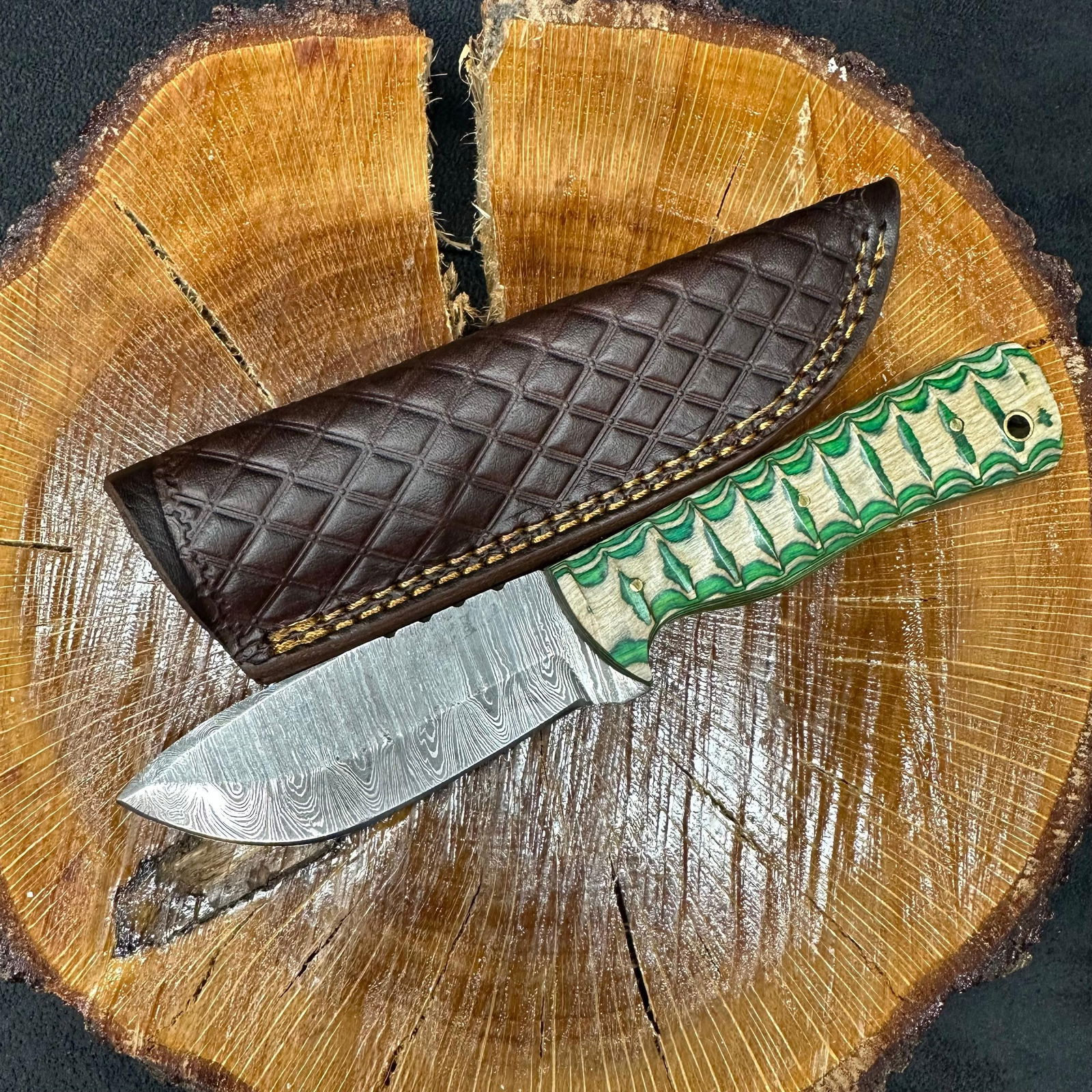 MHS Cutlery Fixed Blade Knife Green and Tan Handle with Sheath Q8: Fixed blade knife by MHS Cutlery featuring a layered patterned steel blade and decorative spine work. The handle has a contoured, multi-colored wood/epoxy resin-style grip with metal mosaic pin accent