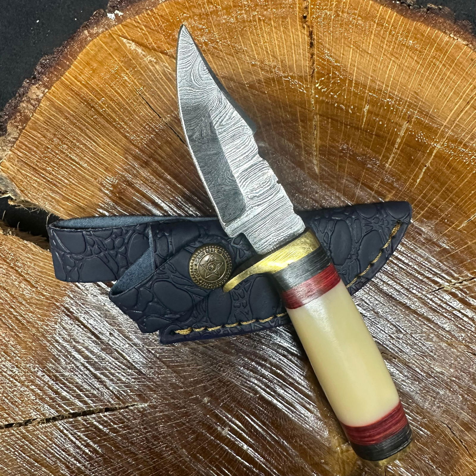 Small Fixed Blade Knife MHS Cutlery Cream Red Black Handle R32: Fixed blade knife by MHS Cutlery featuring a textured steel blade and decorative spine work. The handle has a contoured, cream (bone-toned style), red, and black epoxy resin/wood-style grip with metal