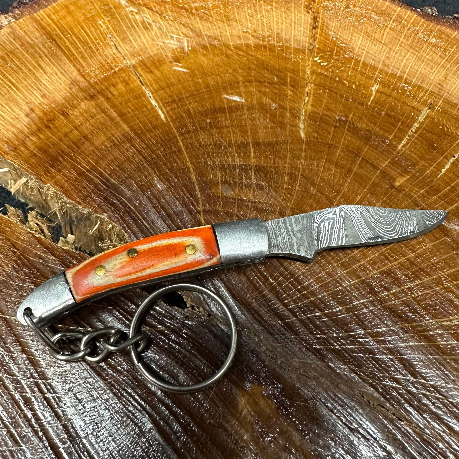 MHS Cutlery Keychain Steel Folding Blade Pocket Knife R54 Orange Handle: Small folding-blade pocket knife featuring a steel blade and a compact epoxy-resin/wood orange-toned handle secured with brass pins. Includes an attached metal key ring for easy carry. Good