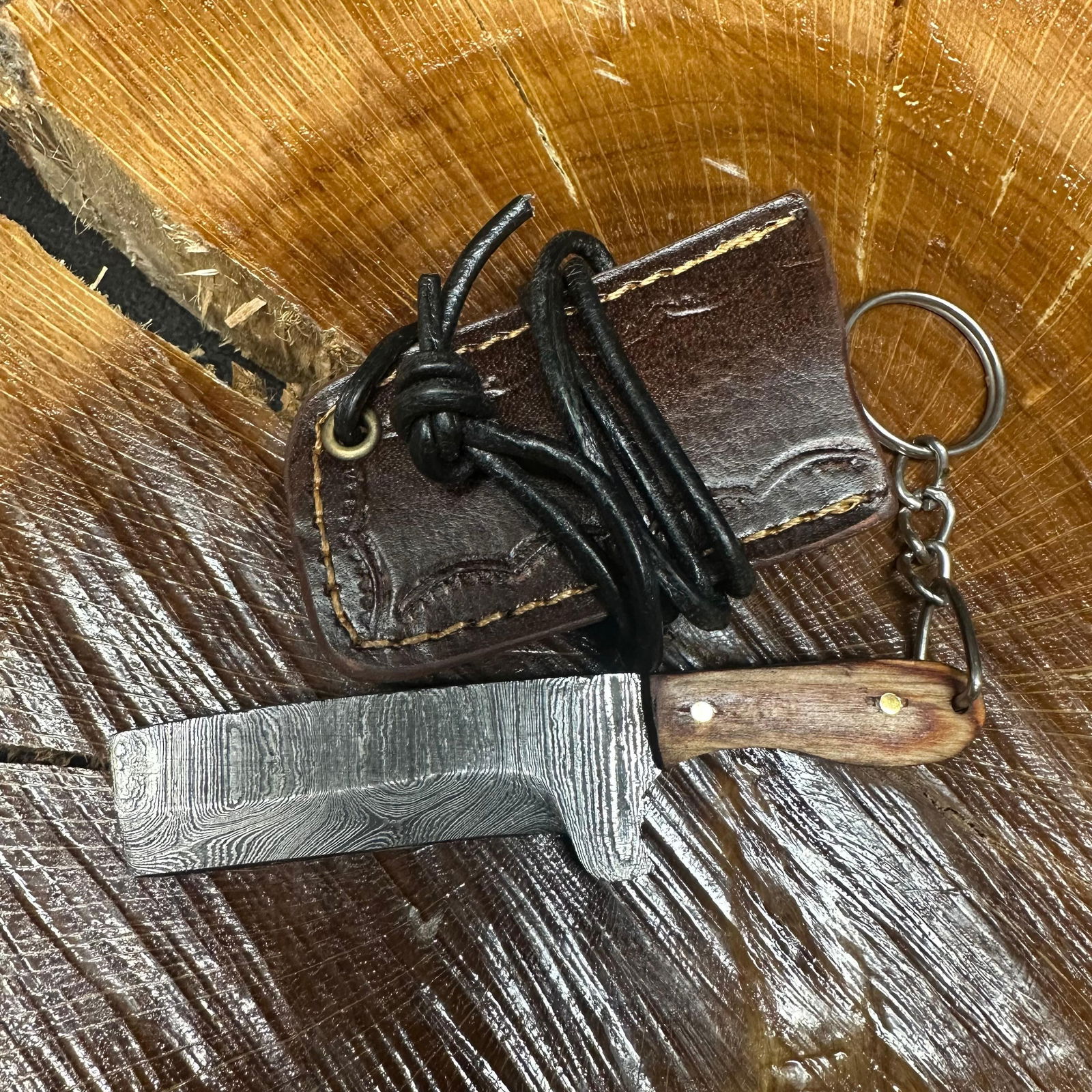 MHS Cutlery Keychain Cleaver Style Blade Knife With Leather Case Necklace R45: Small key chain-sized fixed-blade knife featuring a patterned steel blade and a compact epoxy-resin/wood brown-tone handle secured with brass pins. Includes a fitted brown leather sheath with