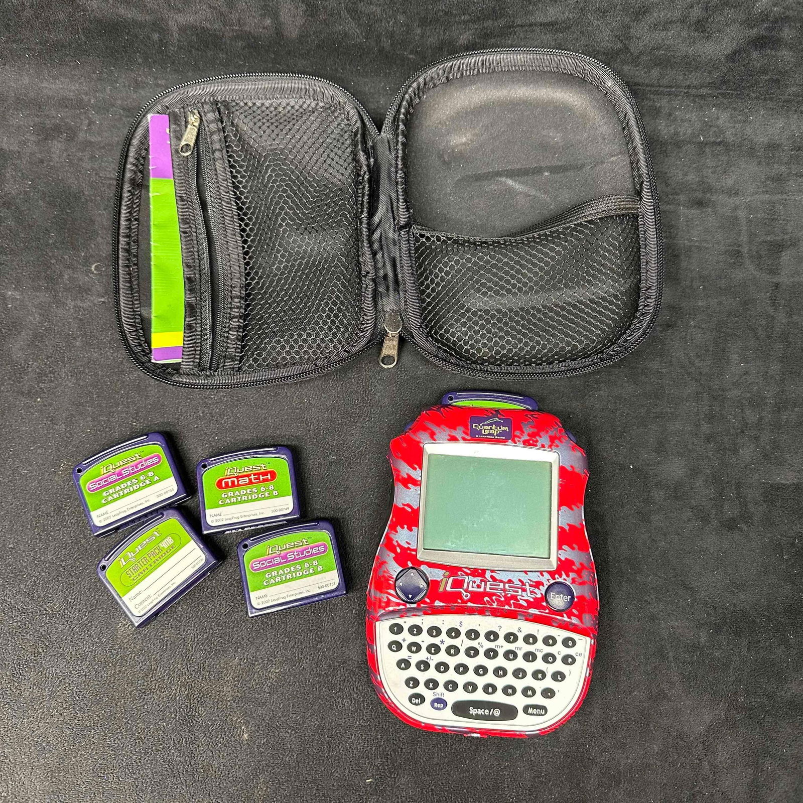 LeapFrog iQuest Handheld Learning System with Cartridges and Case: LeapFrog iQuest handheld learning system in red camo design with QWERTY keyboard. Includes blue protective zippered carrying case, original user guide, and multiple educational cartridges for Math, So