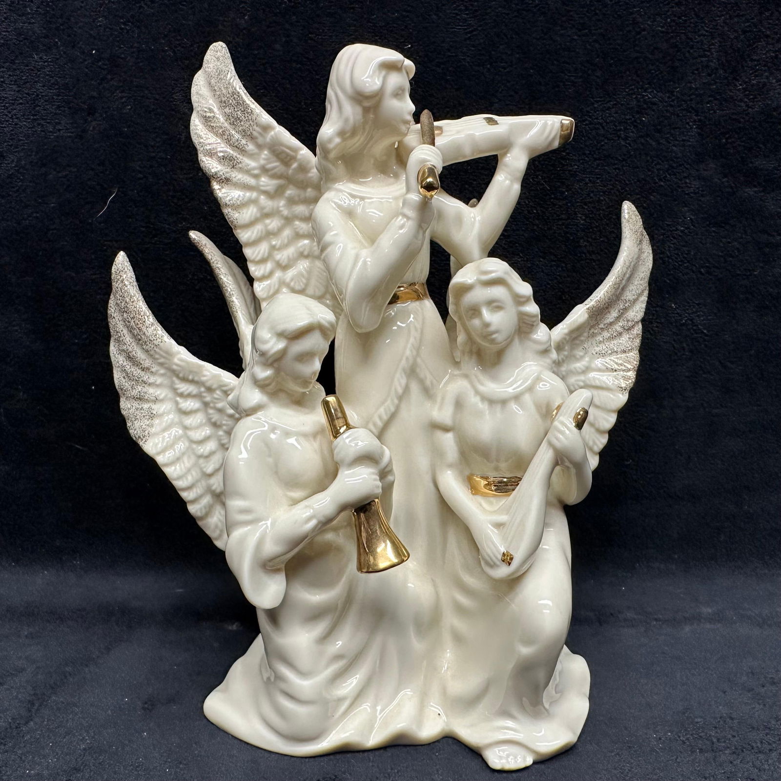 Lenox heavenly Trio Angel Musicians Porcelain Figurine: A Lenox ivory-porcelain angel trio figurine featuring three elegant angels with textured wings and musical instruments, accented with 24K gold detailing. The grouping includes a standing angel playing