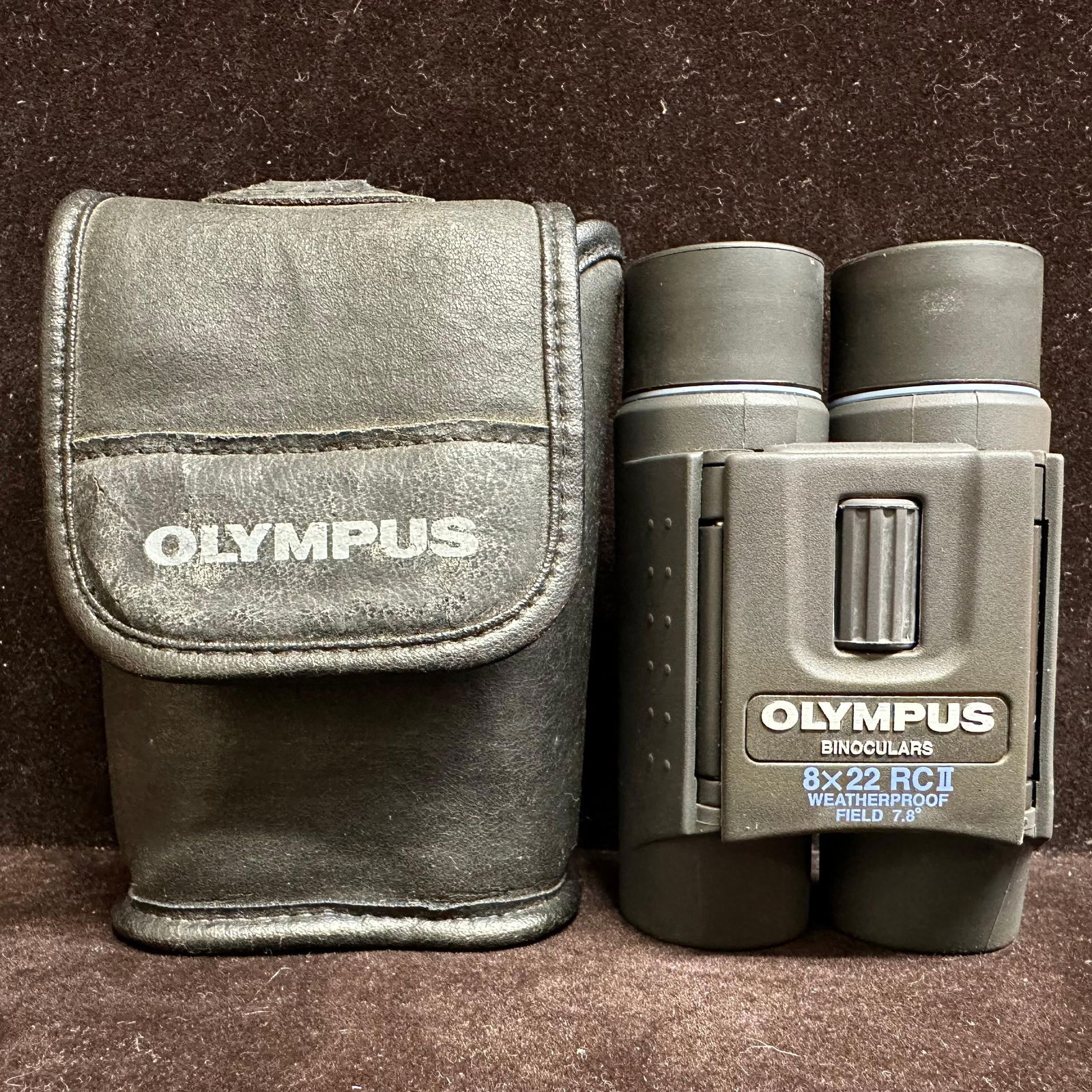 Olympus 8x22 RC II Waterproof Compact Binoculars with Case: Compact Olympus 8x22 RC II binoculars with a folding design. Marked waterproof with a 7.8 field of view. The central focus wheel operates smoothly. Lenses appear clear with light surface scratches and