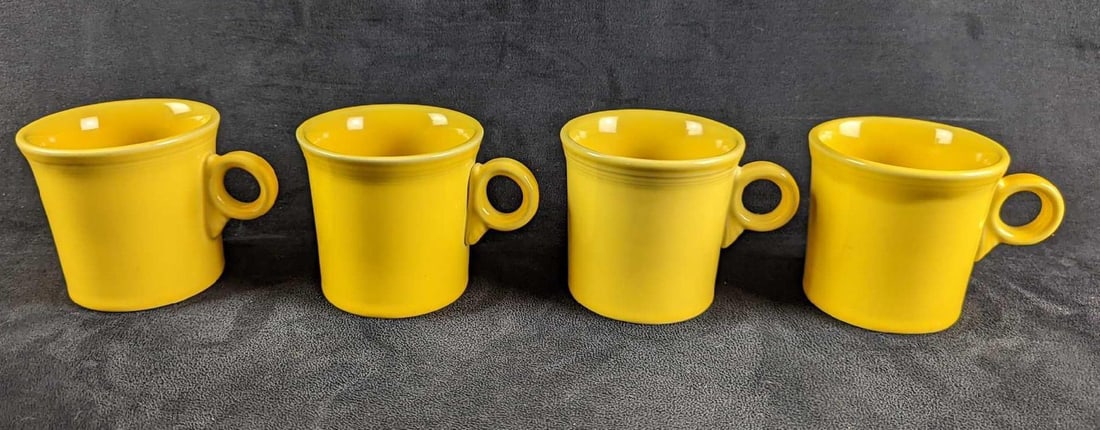4 Yellow Sunflower HLC Fiesta Mugs: 4 Yellow Sunflower HLC Fiesta Mugs. Each is approx 5" x 2 1/2" x 3 1/2" and together they weigh 3.70lbs. The mugs are in a good, used condition with some signs of wear and scratches.