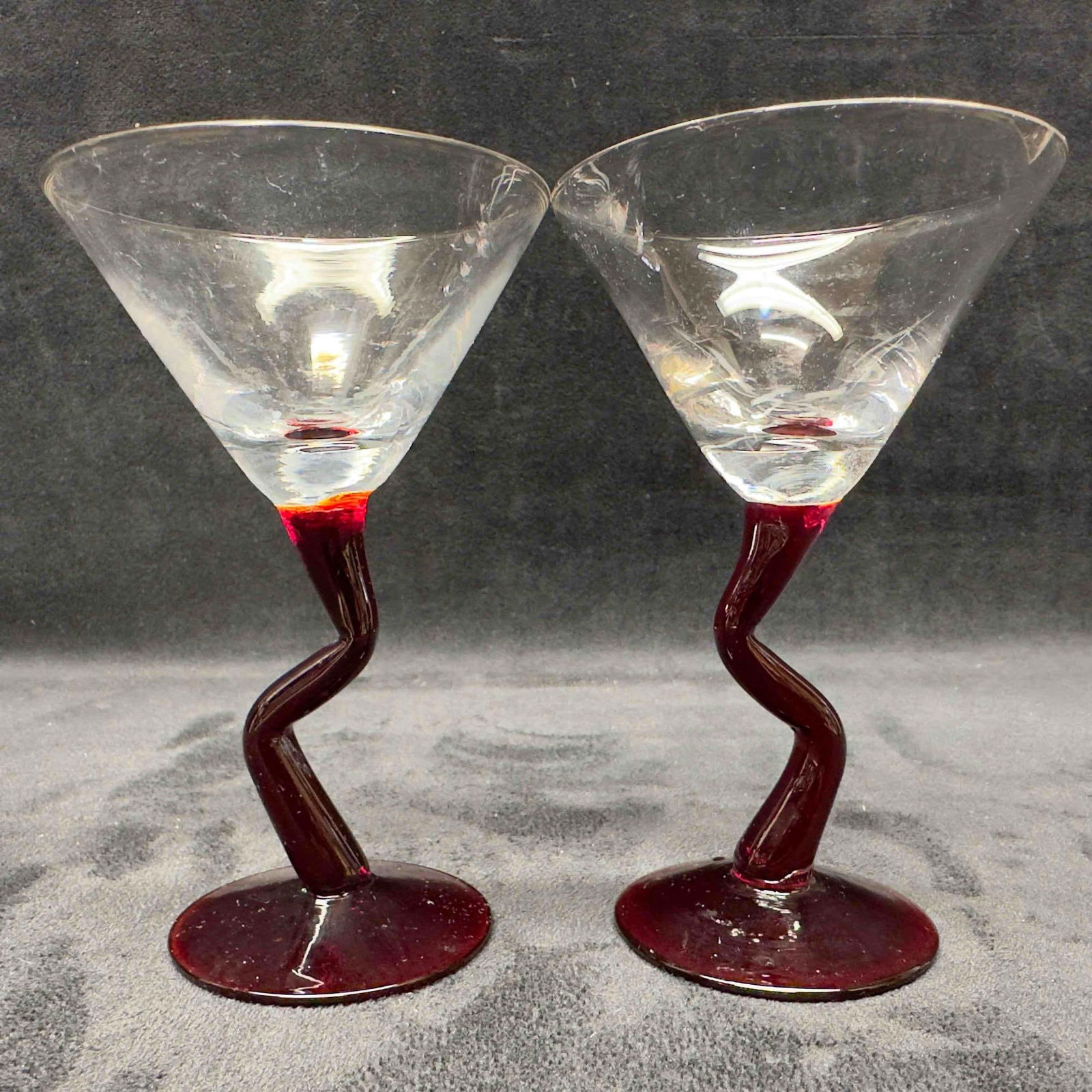 Crystal Clear and Cranberry Red Crooked Stem Cocktail Glasses Set: Crystal Clear and Cranberry Red Crooked Stem Cocktail Glasses Set. This cocktail glass set features two martini style glasses with red crooked stems. These items are in good pre-owned, previously