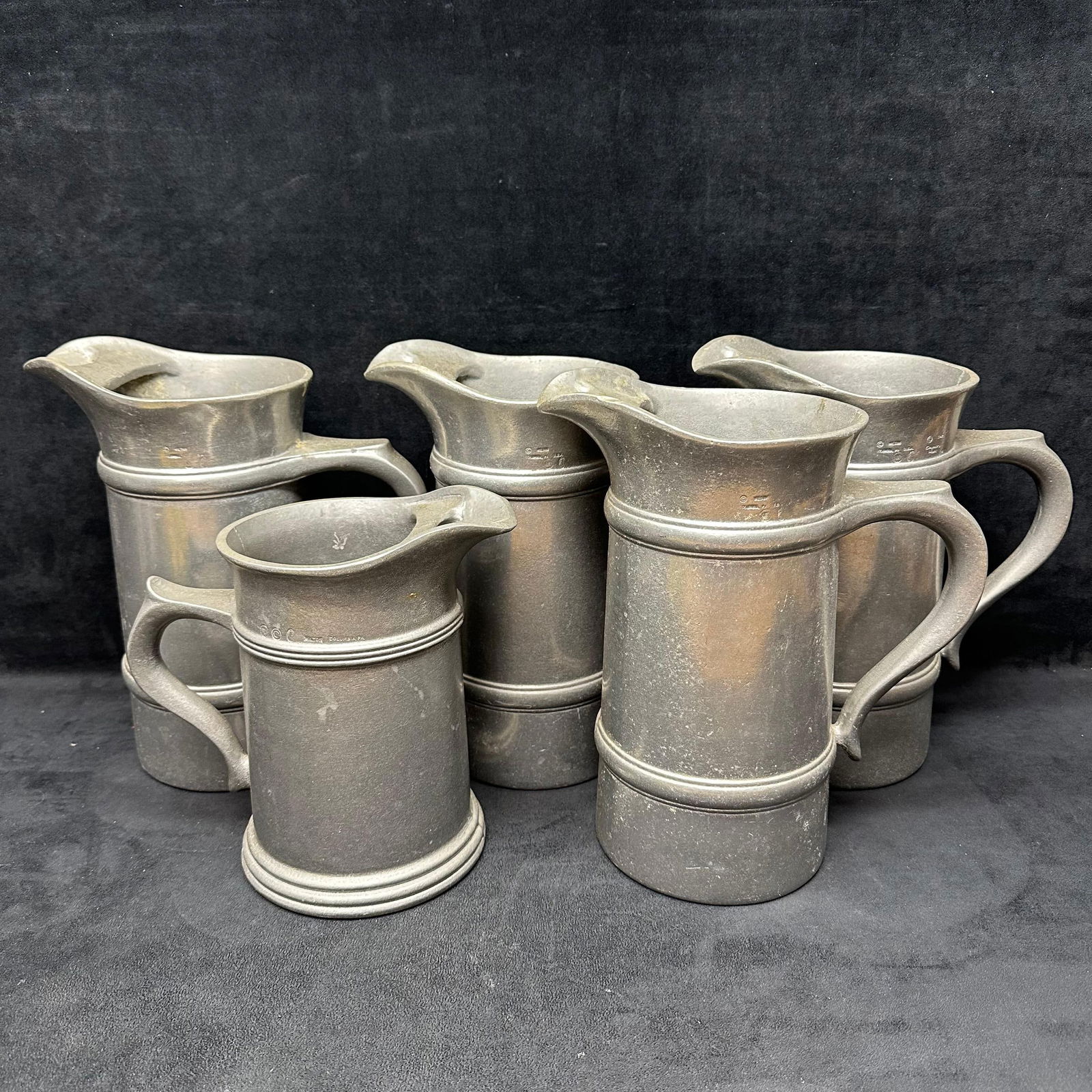 Set of Five Columbia Pewter Tankards Pitcher Set Country Ware Collection: Set of five heavy pewter tankards by Wilton-Columbia, Pennsylvania, part of their Country Ware Collection, dated 1978. Each pitcher features a classic 18th-century-inspired design with double-banded