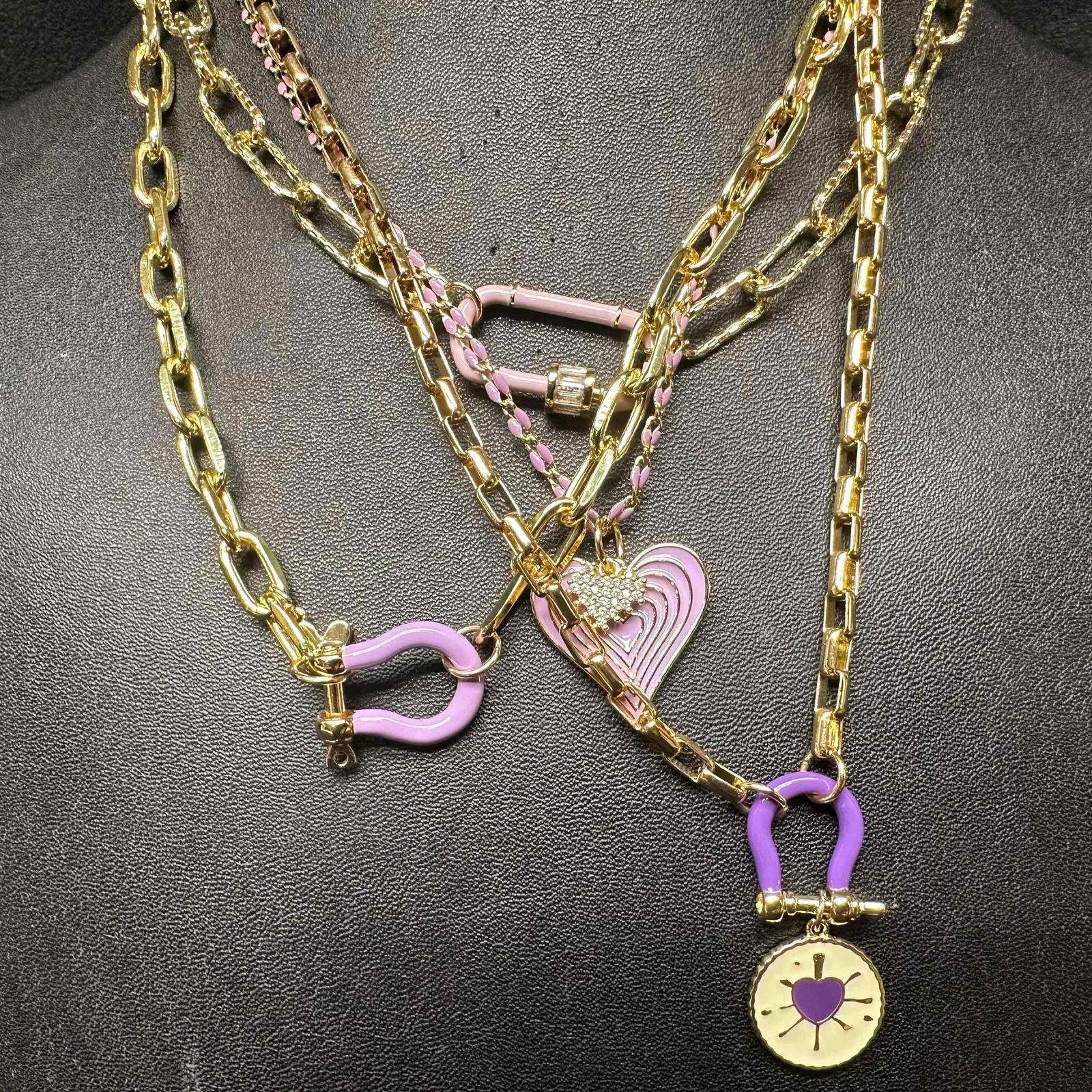 Melania Clara Purple and Gold Chain Assorted Necklace Set Modern Style Necklaces: The Melania Clara necklace set features a magnet clasp closure. The necklaces have magnet extender clasp closures. Each necklace showcase modernist designs with gold tones chain accents. These items