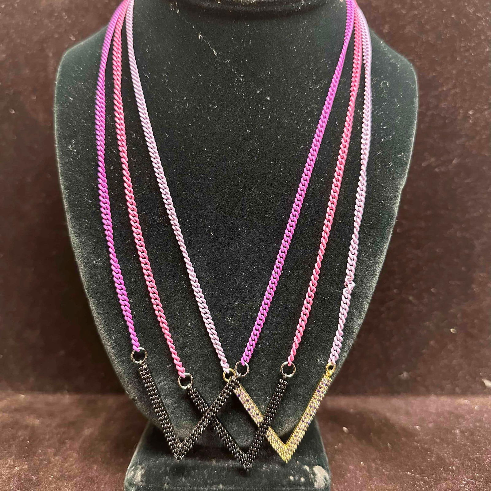 Pink and Purple Chain Melania Clara Assorted Necklace Rhinestone V Set of Three: The Melania Clara necklace set features a magnet clasp closure. The necklaces have magnet extender clasp closures. Each necklace showcase modernist designs. These items are in good pre-owned,