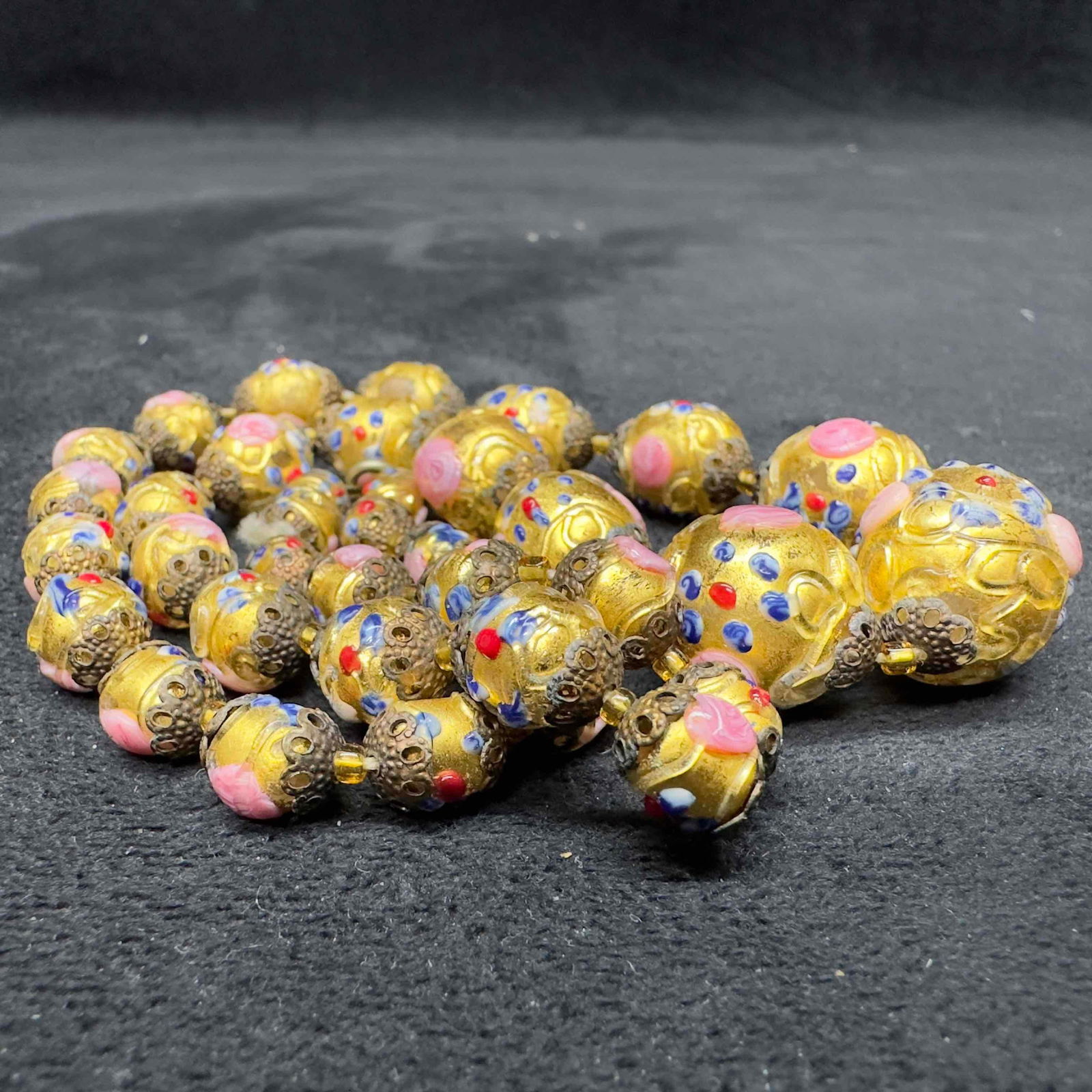 Murano Venetian Art Glass Lamp Work Fiorato Bead Gold Floral Beaded Necklace B59: Murano Venetian Art Glass Lamp Work Fiorato Bead Gold Floral Beaded Necklace B59. Necklace with gold colored glass beads with beautiful designs on each. The necklace features floral accents. The