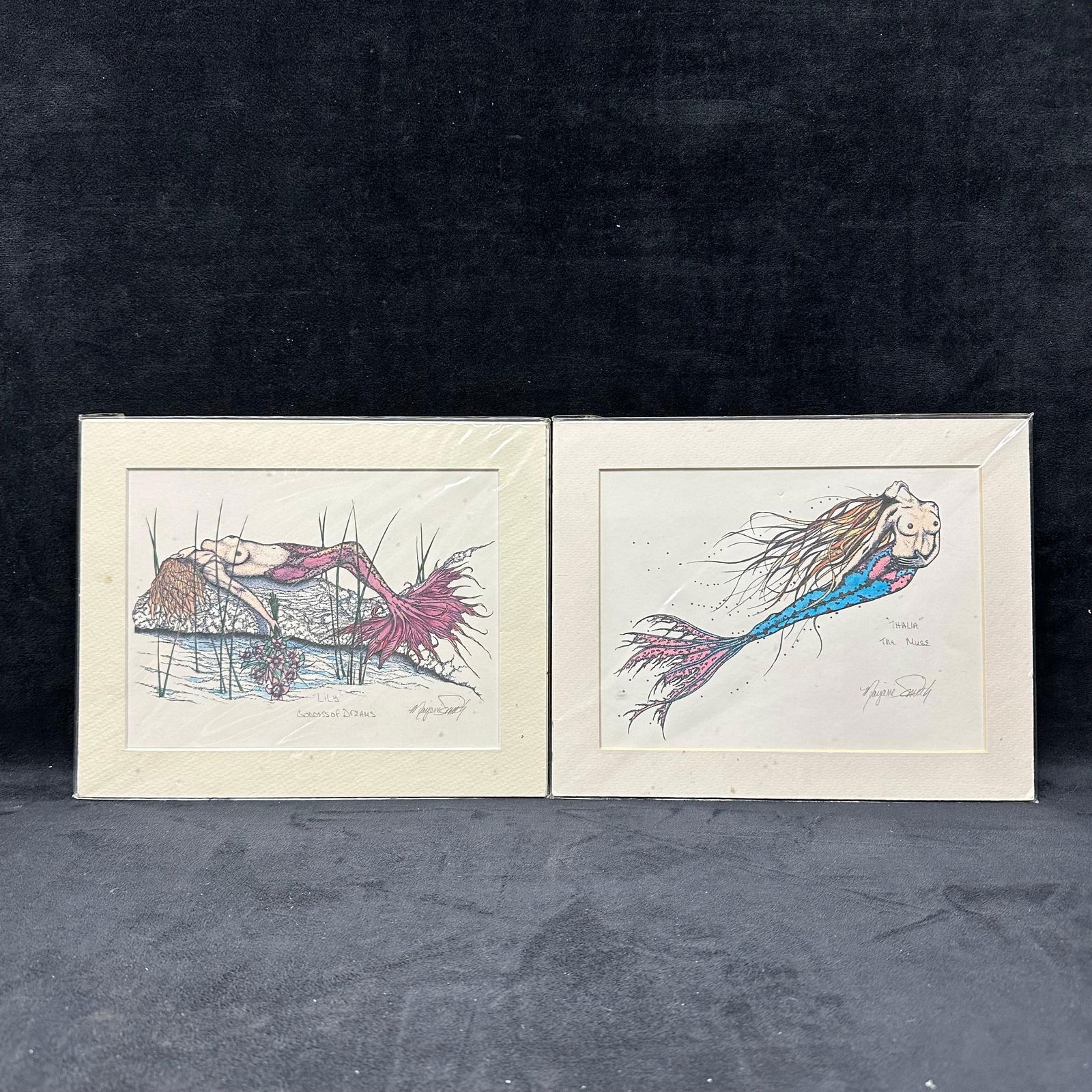 Pair Mermaid Art Prints Signed by Marjorie Smith Lily Goddess of Dreams and Thalura The Muse: Pair of whimsical fantasy art prints depicting mermaid figures, titled Lily Goddess of Dreams and Thalura the Muse. Both appear signed in the image and are matted and under protective wrap. Labels on