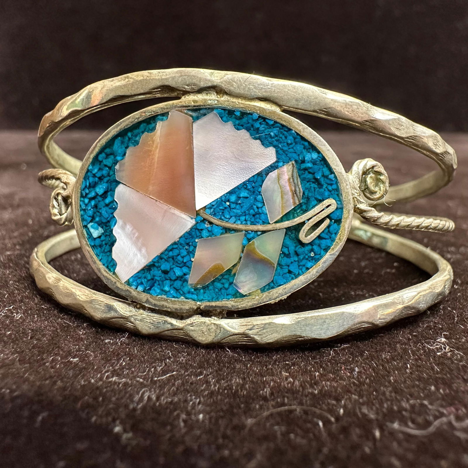Alpaca Mexico Turquoise Composite and Mother of Pearl Inlay Cuff Bracelet: Vintage cuff bracelet marked Alpaca Mexico. Features an oval inlay design with crushed turquoise composite and mother-of-pearl style shell pieces. Textured double band with scroll accents.