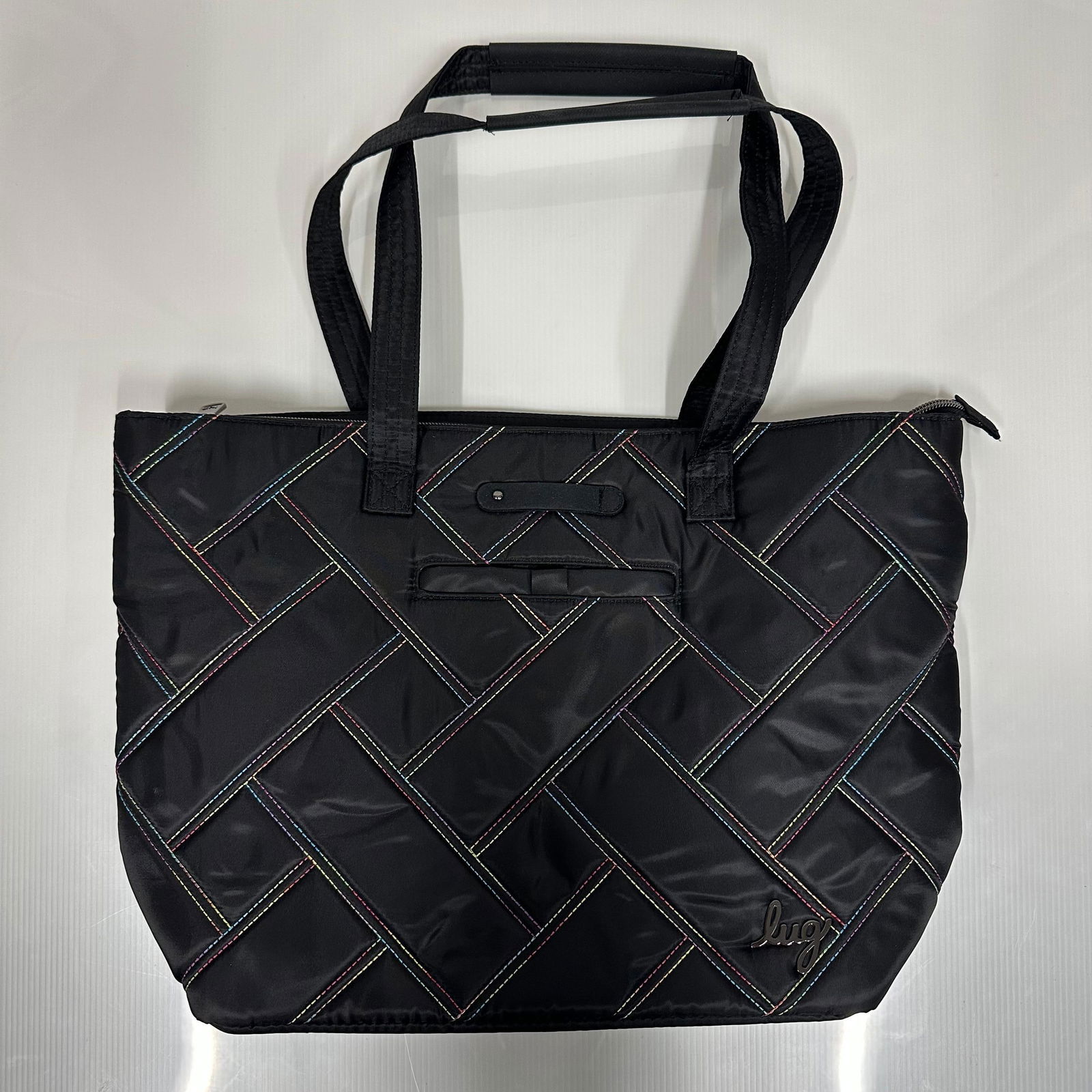 Lug Skyliner Black Quilted Tote Bag with Rainbow Stitching: Lug Skyliner tote bag in black nylon with multicolor rainbow contrast stitching in a quilted geometric pattern. Double top handles with padded grip. Zip top closure. Front exterior slip pocket. Inter