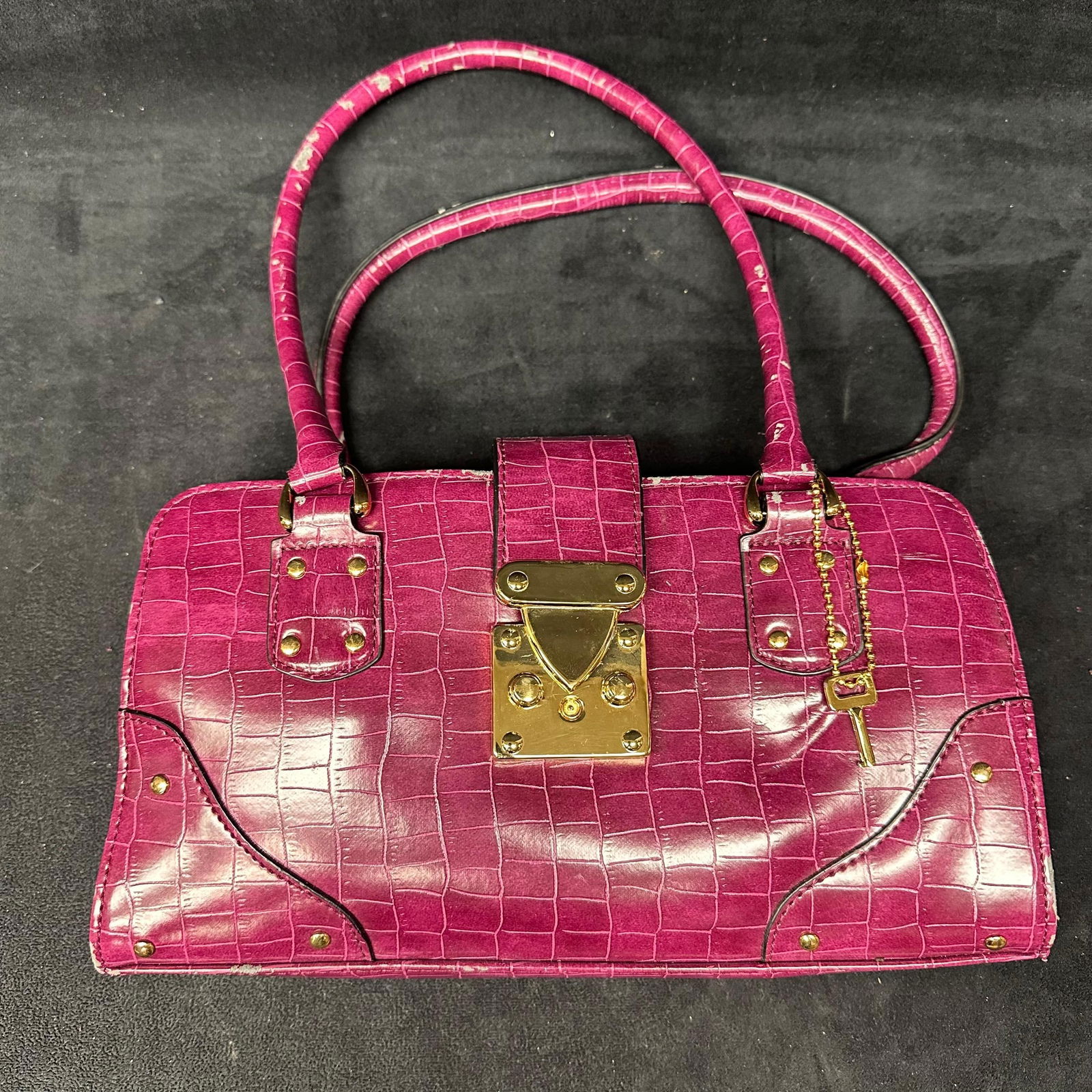 Pink Faux Crocodile Embossed Satchel Handbag: Structured pink satchel featuring faux crocodile embossed finish, dual top handles, and gold-tone push-lock closure. Includes decorative key charm and gold-tone hardware. Interior zip compartment. Vis