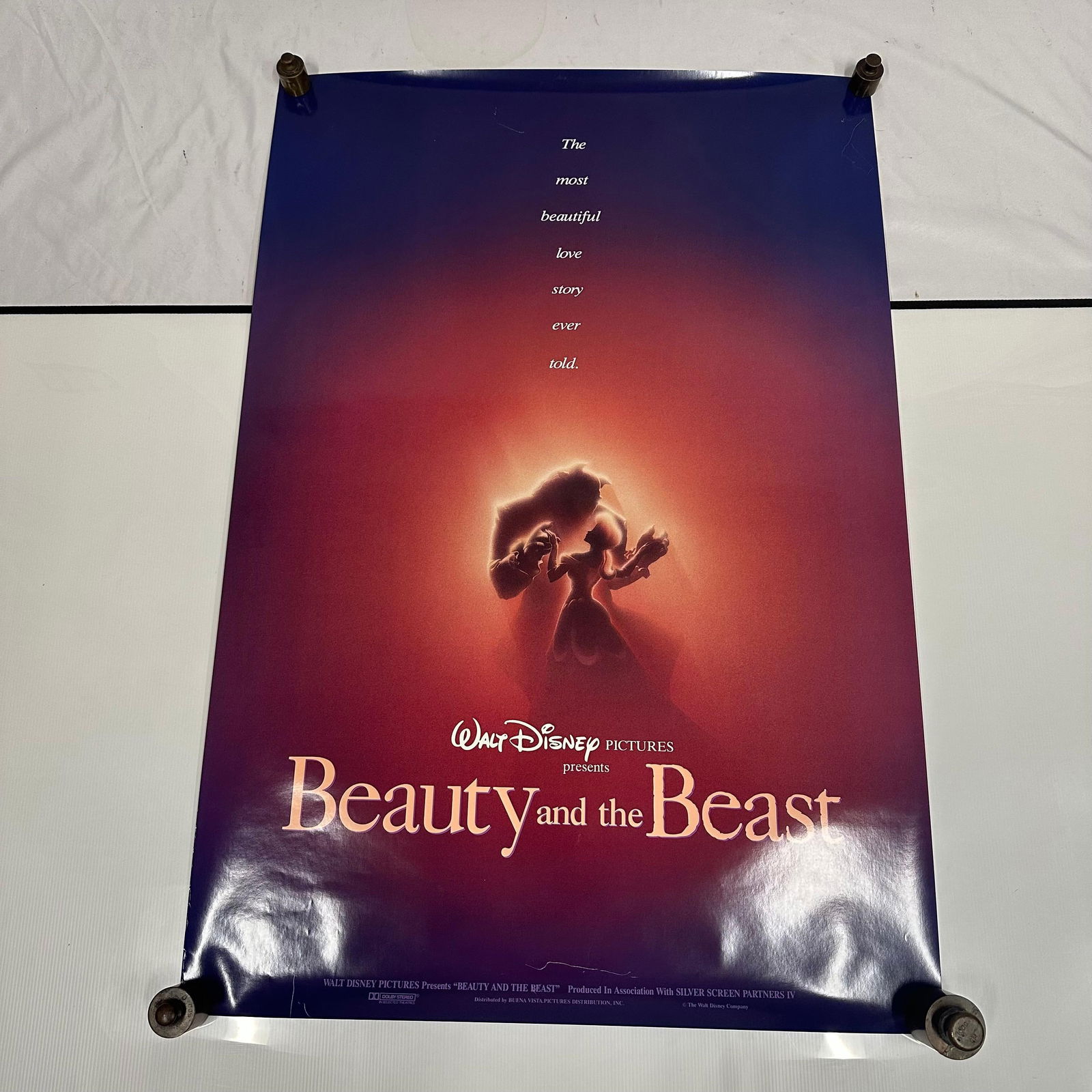 Walt Disney Pictures Beauty and the Beast Original Movie Poster: Original theatrical one-sheet double-sided movie display poster for Walt Disney Pictures’ Beauty and the Beast (1991). Features the iconic silhouette artwork of Belle and the Beast dancing against a
