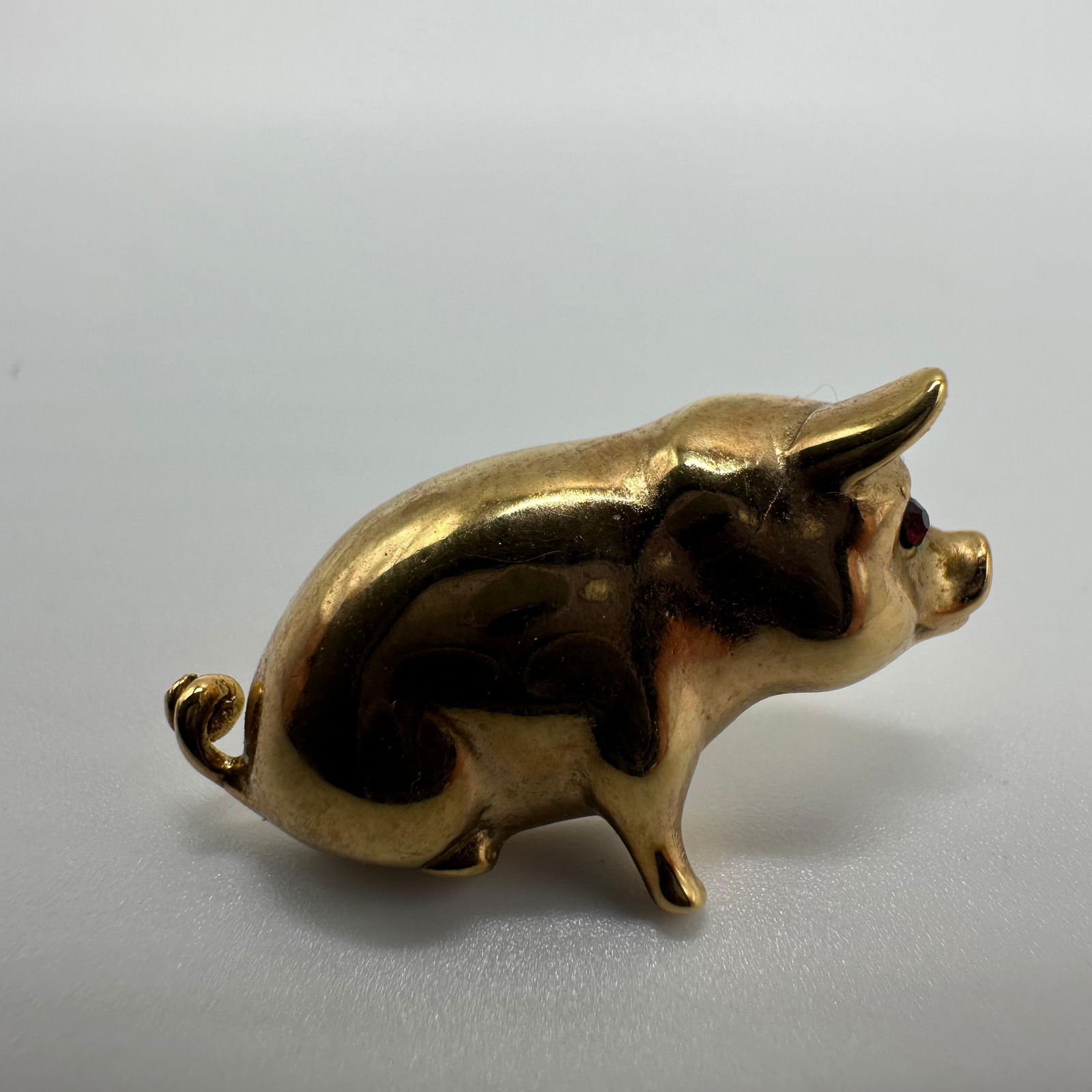 Gold Tone Pig Red Glass Accent Eye Costume Jewelry Pin: Gold-toned pig-form pin accessory featuring an inset red glass eye. Hollow underside with a central metal spike pin. Polished gold-toned finish with natural patina and light surface wear consistent