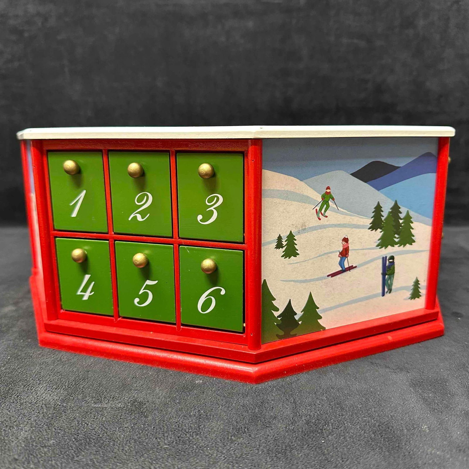 Skating Party Advent Calendar Christmas Holiday Decor Mini Figures and Ornaments: Holiday decor piece made of wood set up in a lazy Susan style spinning motion with twenty four small comparments. There is a small mini figure or ornament in each. The top has a ice skating theme to