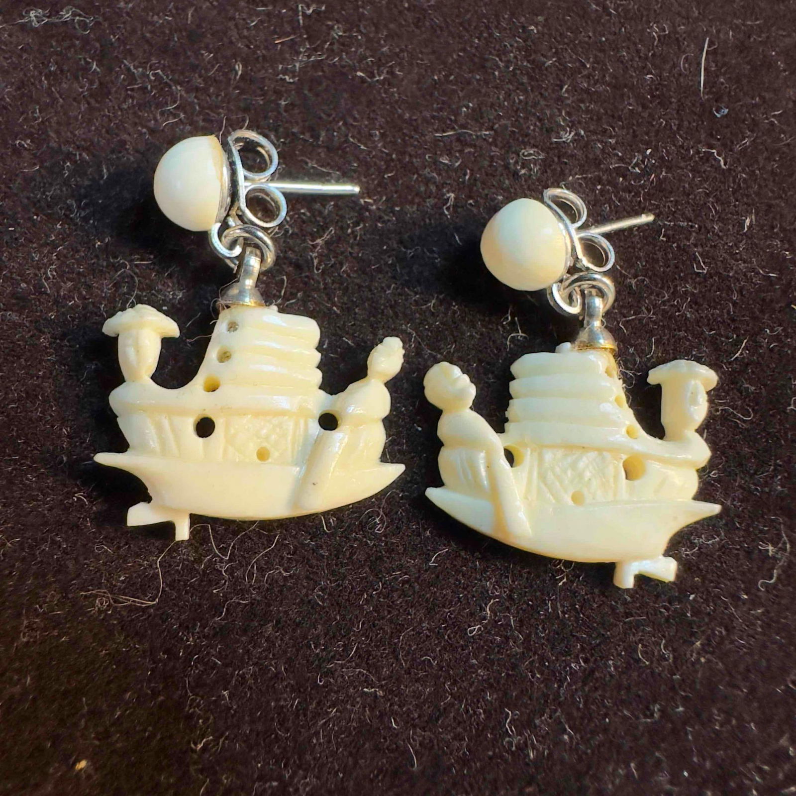 Hand Carved Bone Boat Dangle Drop Earrings: Hand Carved Bone Boat Drop Earrings. The earrings feature a butterfly clutch clasp closure. This item is in good pre-owned, previously displayed condition with light wear, and surface scratches.