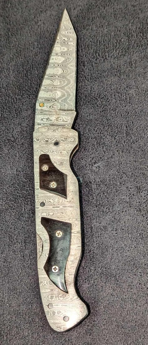 Damascus Steel Fold Up Black Bone Handle Knife Retired B: Damascus Steel Fold Up Black Bone Handle Knife Retired B. Here is a fold-up knife made of imported Damascus steel with a black natural bone handle. These were made in very limited batches by a small