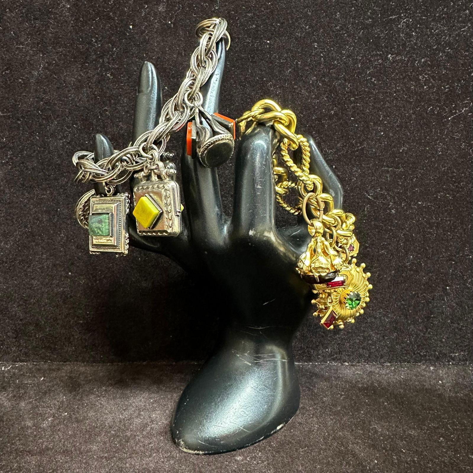 Pair of Vintage Charm Bracelets Silver and Gold Tone with Glass Stone Charms V18: A lot of two vintage charm bracelets. A silver-tone bracelet with square and geometric charms set with green and yellow glass faux stones. Includes small fob-style charm with red and black accents. He