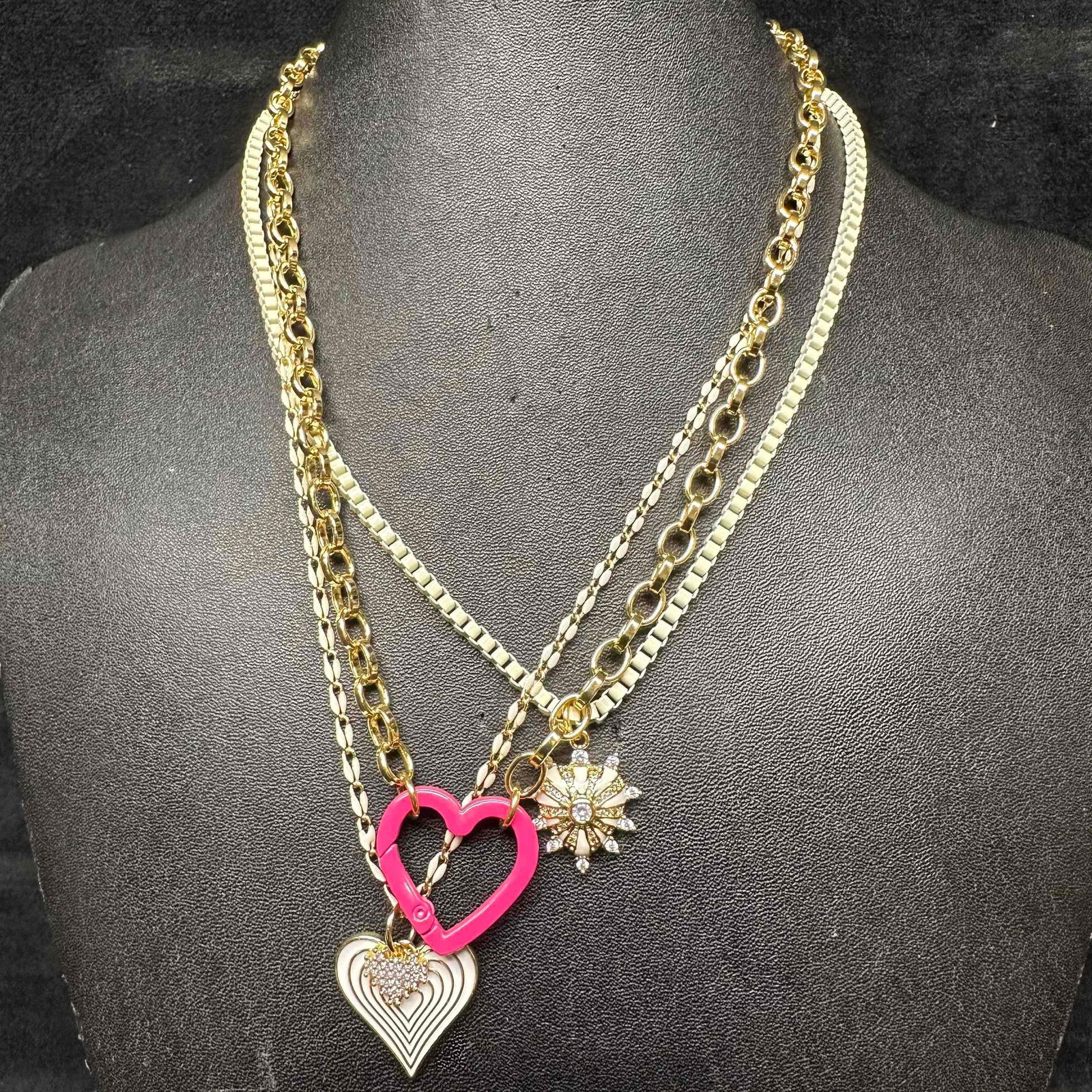 Rhinestone Heart Gold Tone Chain Melania Clara Necklace Mixed Set of Three: The Melania Clara necklace set features a magnet clasp closure. The necklaces have magnet extender clasp closures. Each necklace showcase modernist designs with gold toned chain, heart, and