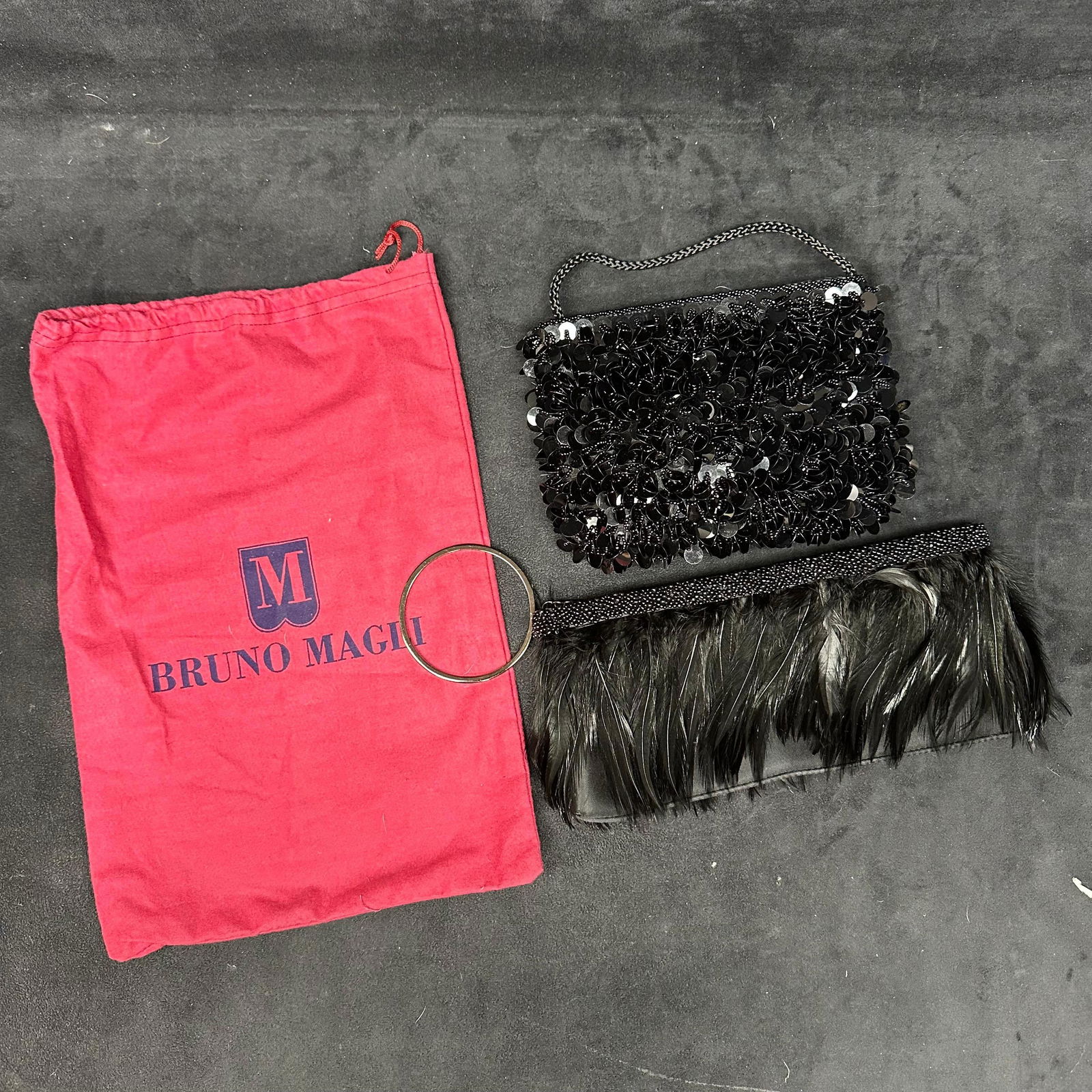 Lot of Two Black Evening Bags Sequin Beaded Handbag and Feather Trim Clutch: The lot includes two black evening bags. The first is a small handbag fully embellished with black sequins and beadwork, featuring a short beaded handle. The second is a black clutch accented with bla