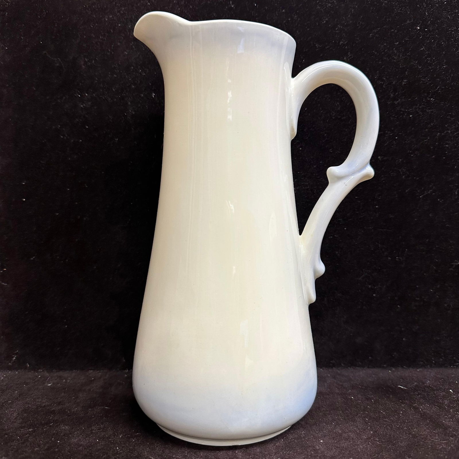 Vintage White Glazed Blue Hue Accent Ceramic Pitcher Handle Marked G.B. 1988: Vintage ceramic pitcher featuring a tall, tapered form with a gently flared spout and applied loop handle with thumb rest detail. Finished in a glossy white glaze with a blue hue accent. Underside mar