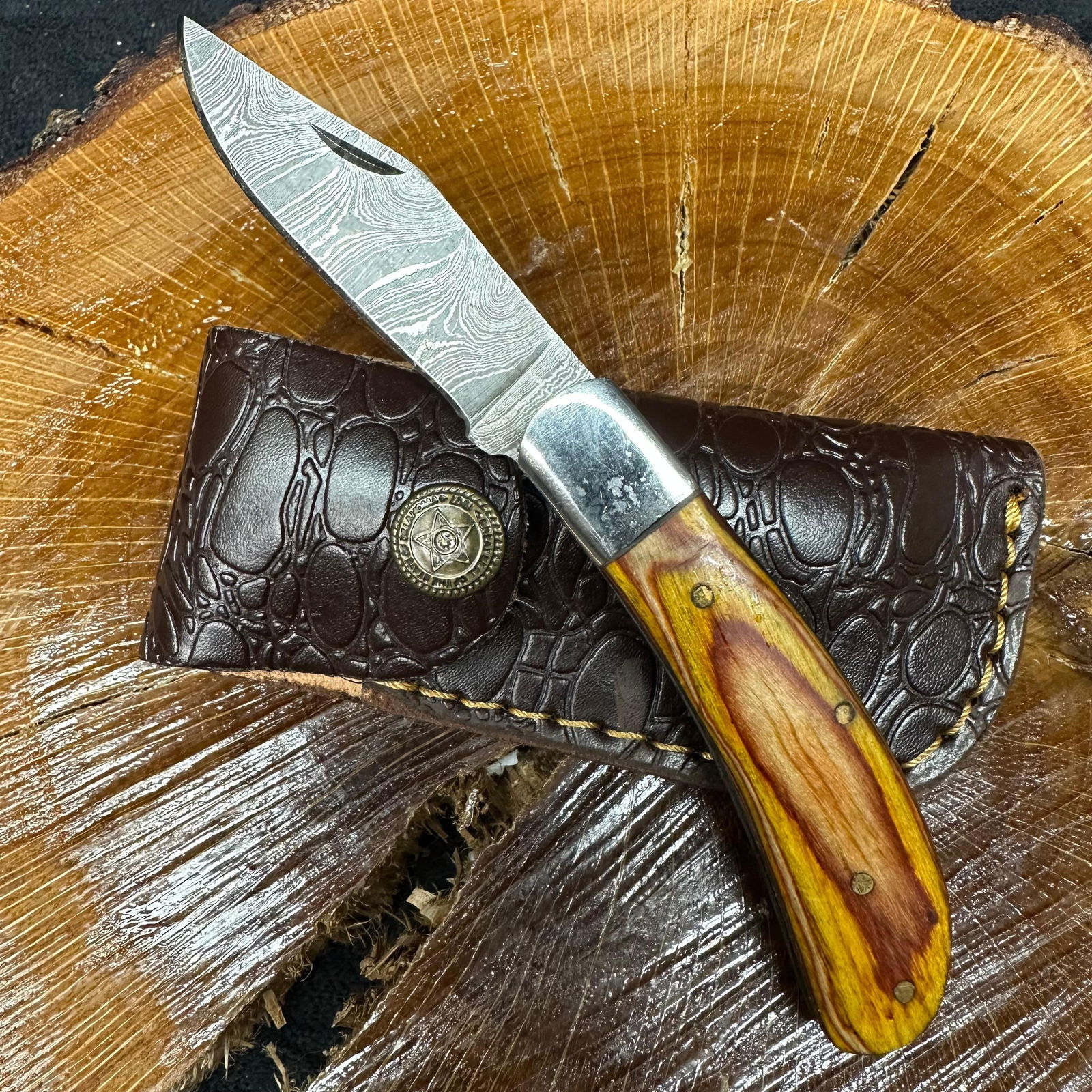 MHS Cutlery Steel Folded Blade Pocket Knife Wood Style Handle Design Q79: Folding blade pocket knife by MHS Cutlery featuring a layered patterned steel blade and decorative spine work. The handle has a contoured, wood/resin-style grip with metal mosaic pin accents.