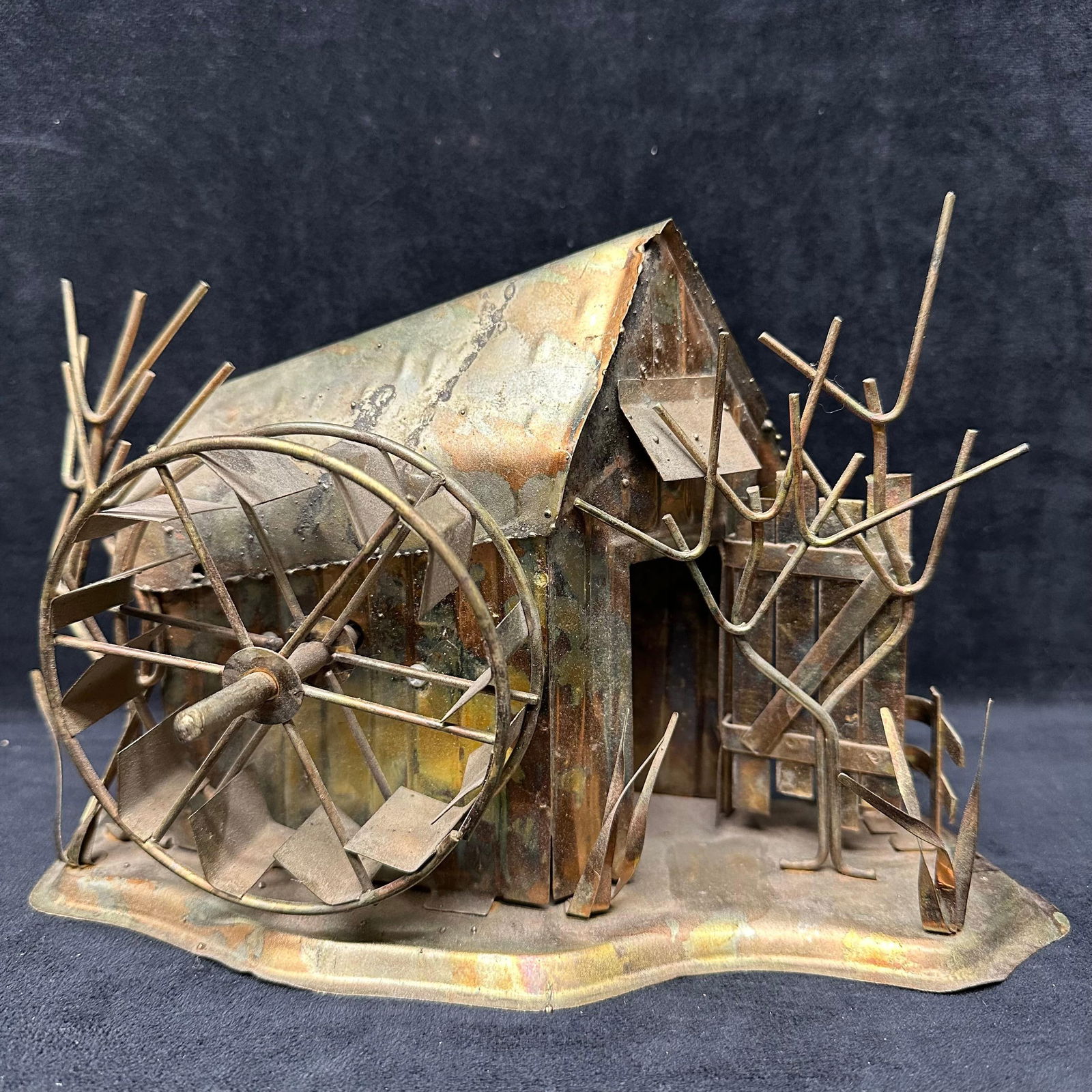 Handcrafted Metal Barn and Water Wheel Sculpture with Trees Rustic Folk Art: Handcrafted metal folk art sculpture depicting a rustic barn with an attached water wheel and surrounding trees. Constructed from hand-cut and shaped metal sheets and rods, mounted on a formed metal b