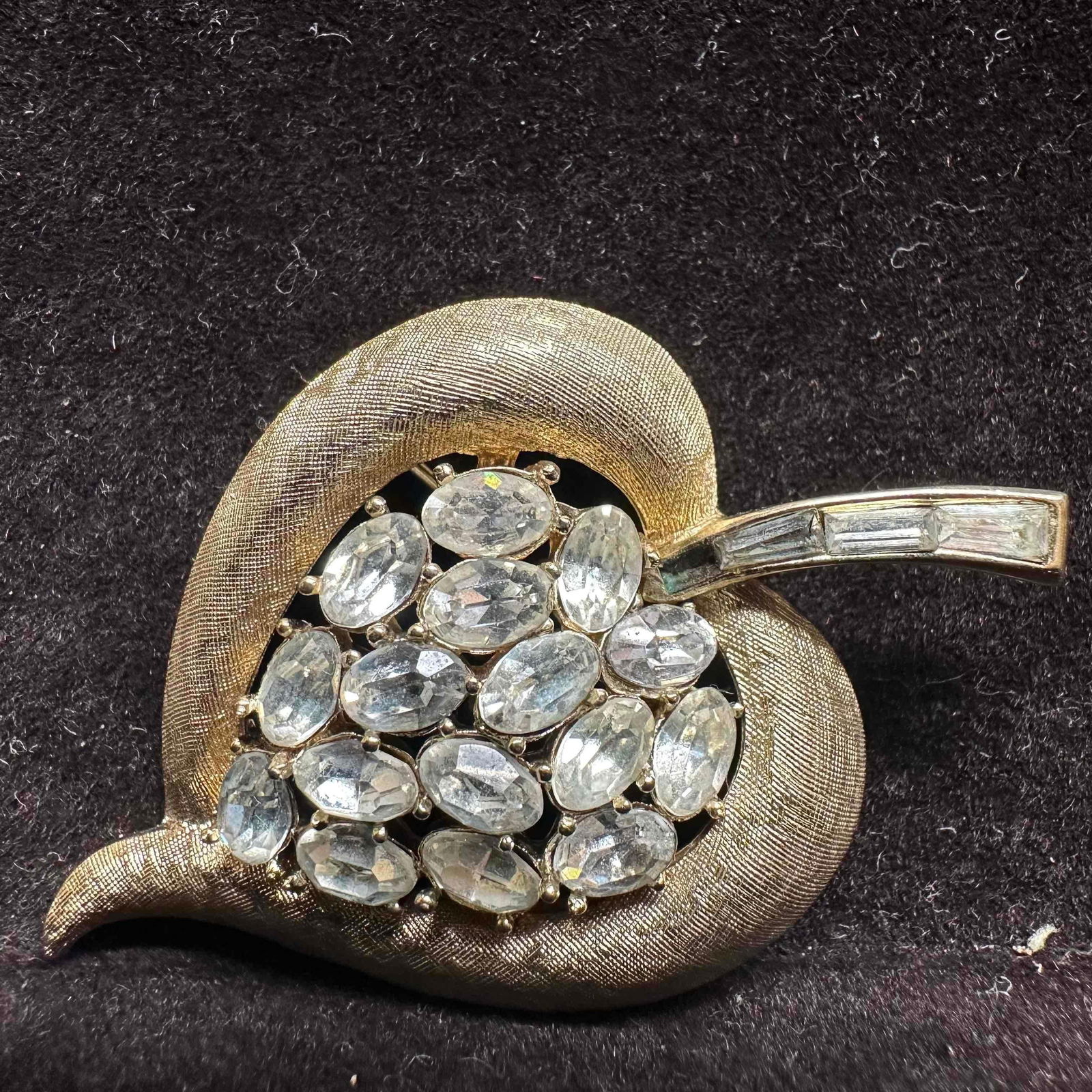 Crown Trifari Rhinestone Leaf Brooch Gold-Tone with Clear Stones Signed: Elegant vintage Crown Trifari brooch in the shape of a leaf. Gold tone textured metal set with clear oval rhinestones and baguette rhinestones along the stem. Signed Crown Trifari on the reverse with