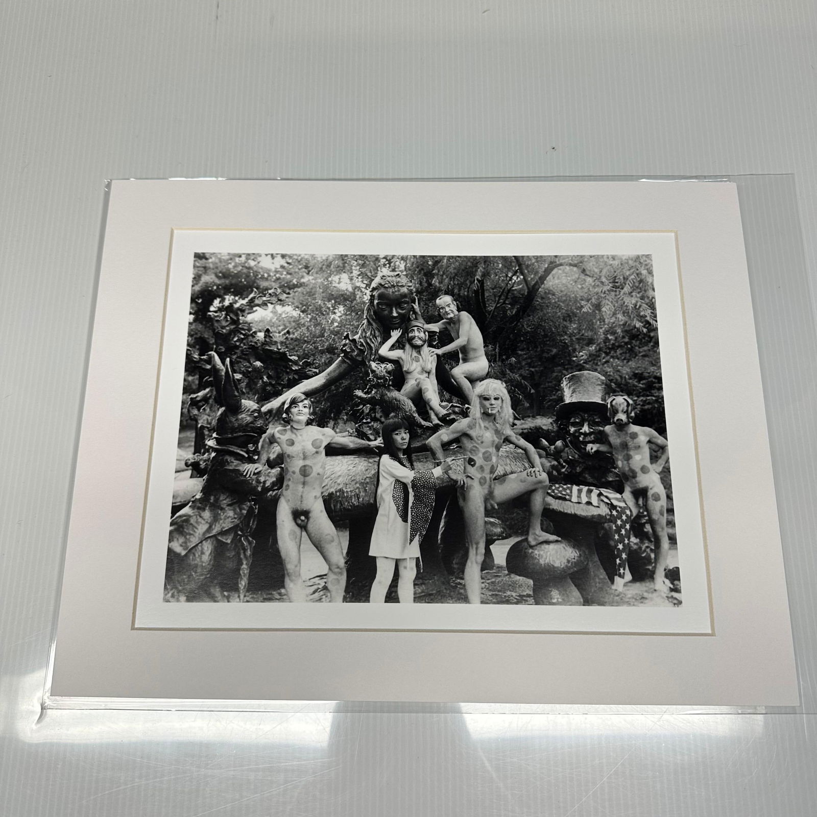 Yayoi Kusama Black and White Photo Print Anatomic Explosion Happening Nude Matte: Black and white photographic print depicting Yayoi Kusama posed with polka-dotted nude models in an outdoor sculptural statue, Alice in Wonderland, setting in New York's Central Park. Print is pre