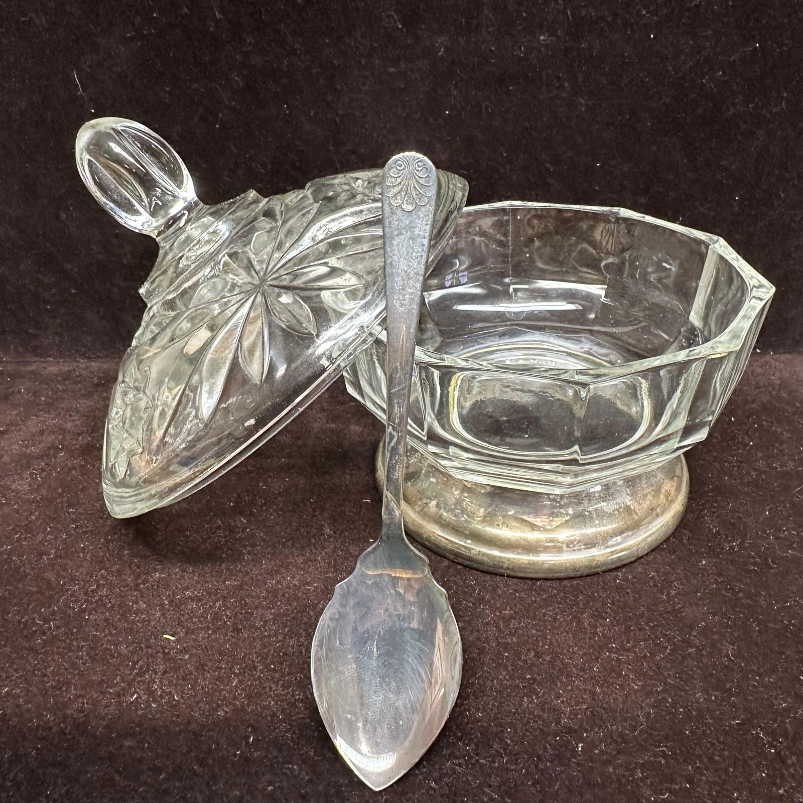 Cut Italy Glass Lidded Sugar Bowl Dish with Silver Plate Base and Spoon: Vintage clear-cut glass-covered sugar bowl featuring pressed starburst and geometric pattern throughout. Domed lid with faceted finial. Bowl rests in a silver-plated pedestal base. Includes