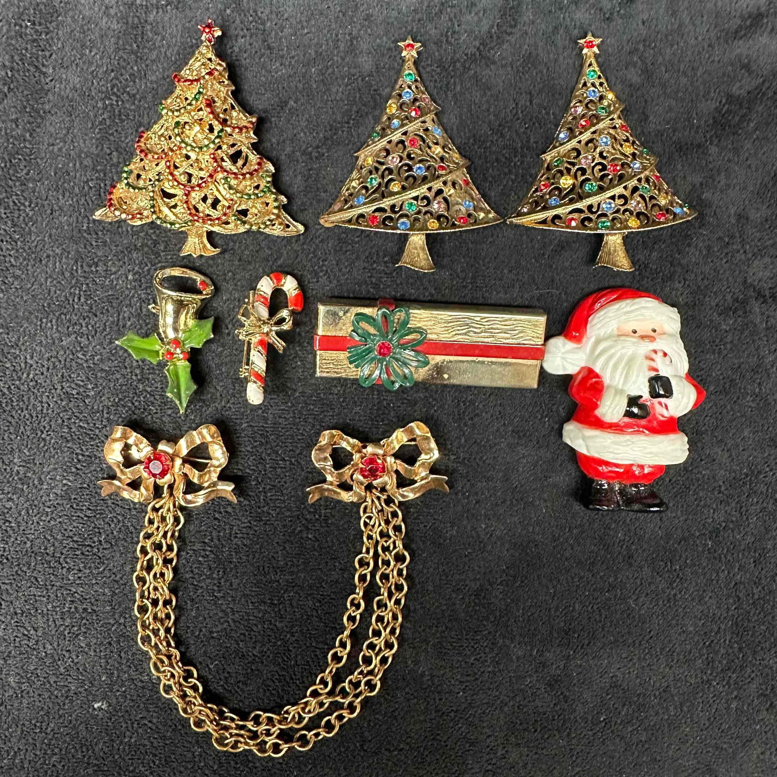Holiday Christmas Tree Gift Santa Candy Cane Ribbon Brooch Set Eight: Two Christmas tree brooches are missing the clasp. One brooch is a set with two ribbons connected by a chain. Total of eight (8) brooches. These items are in good pre-owned, previously displayed