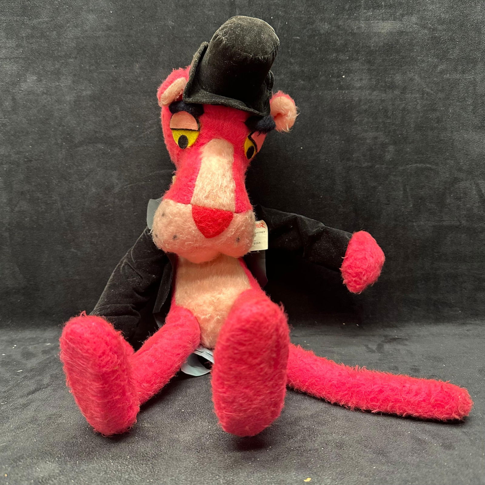 Vintage Pink Panther Plush Toy in Tuxedo and Top Hat Mighty Star 1984: Vintage Pink Panther plush character toy featuring a black tuxedo jacket and top hat. Manufactured by Mighty Star, dated 1984. Soft plush construction with original sewn-in tags present. Poseable